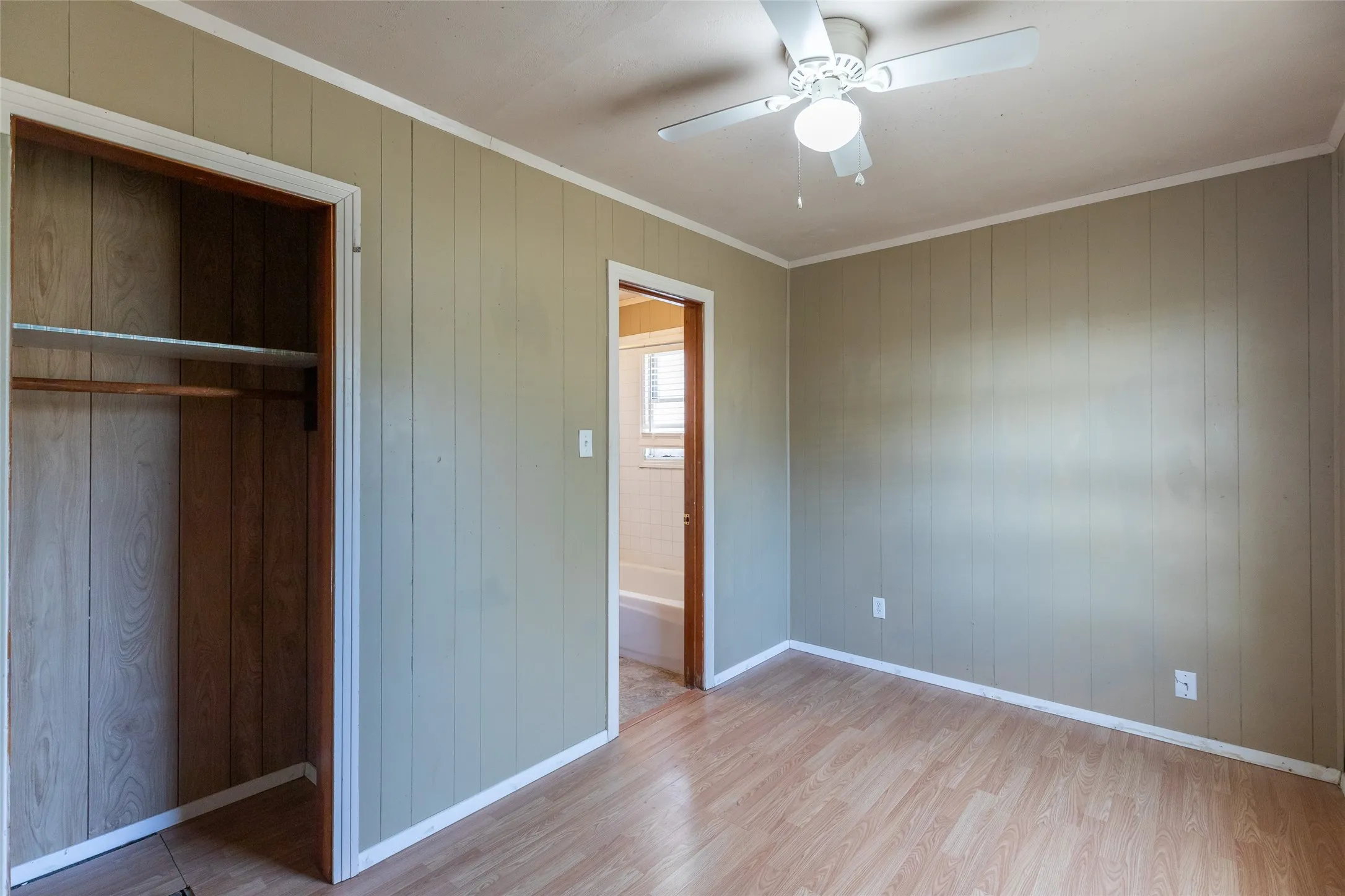 Spacious room featuring wood-finish flooring, paneling walls, and white trim