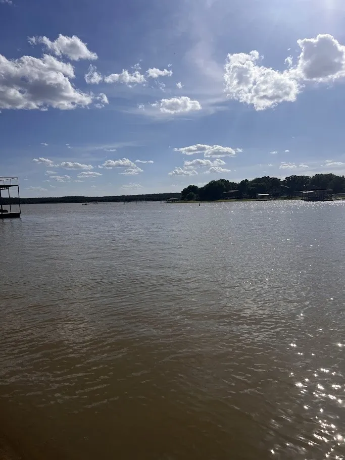 Expansive waterfront setting featuring a tranquil body of water, distant tree-lined shore, and a multi-level boat dock