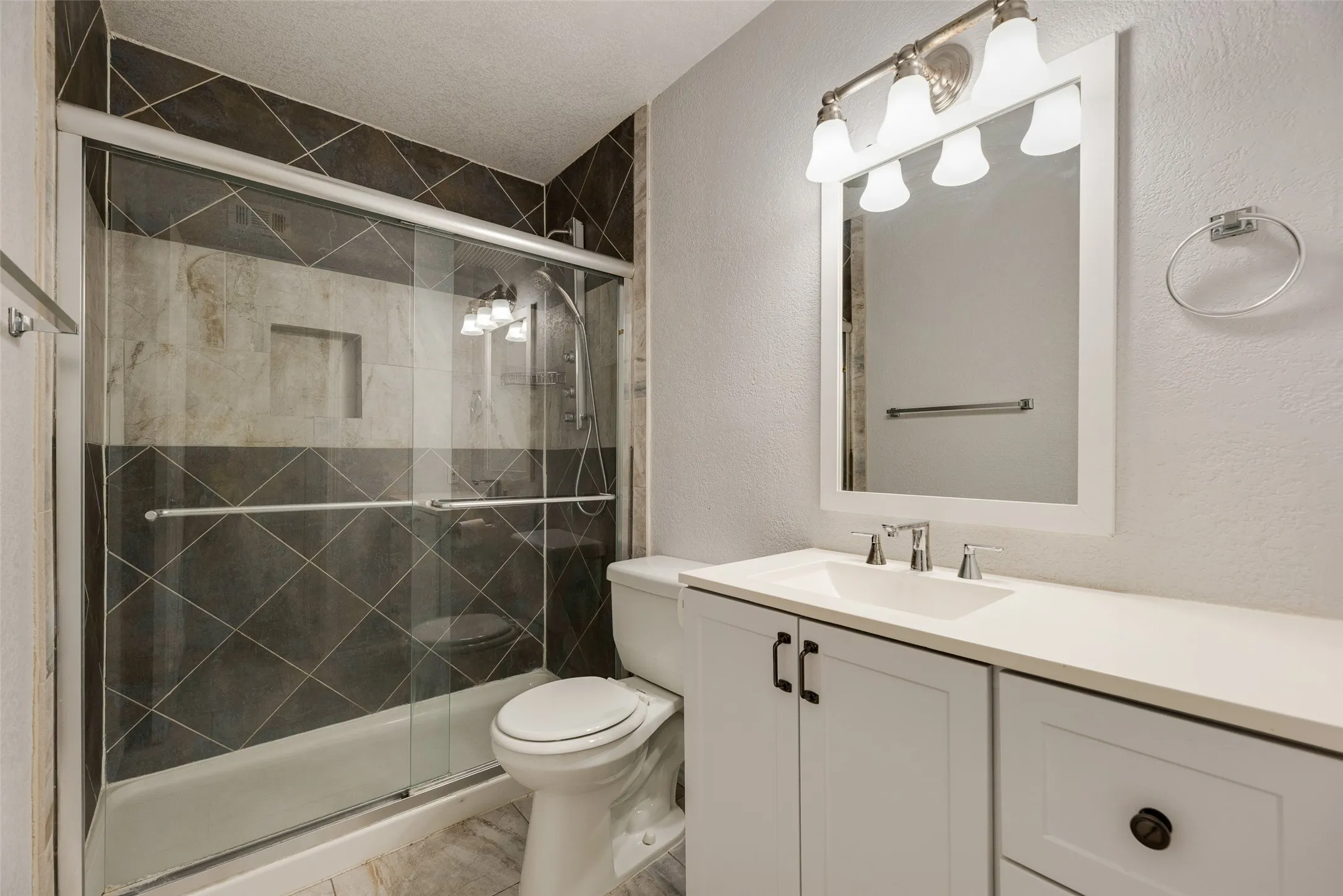 Bathroom featuring a white vanity with an integrated sink, polished chrome faucet, and framed mirror