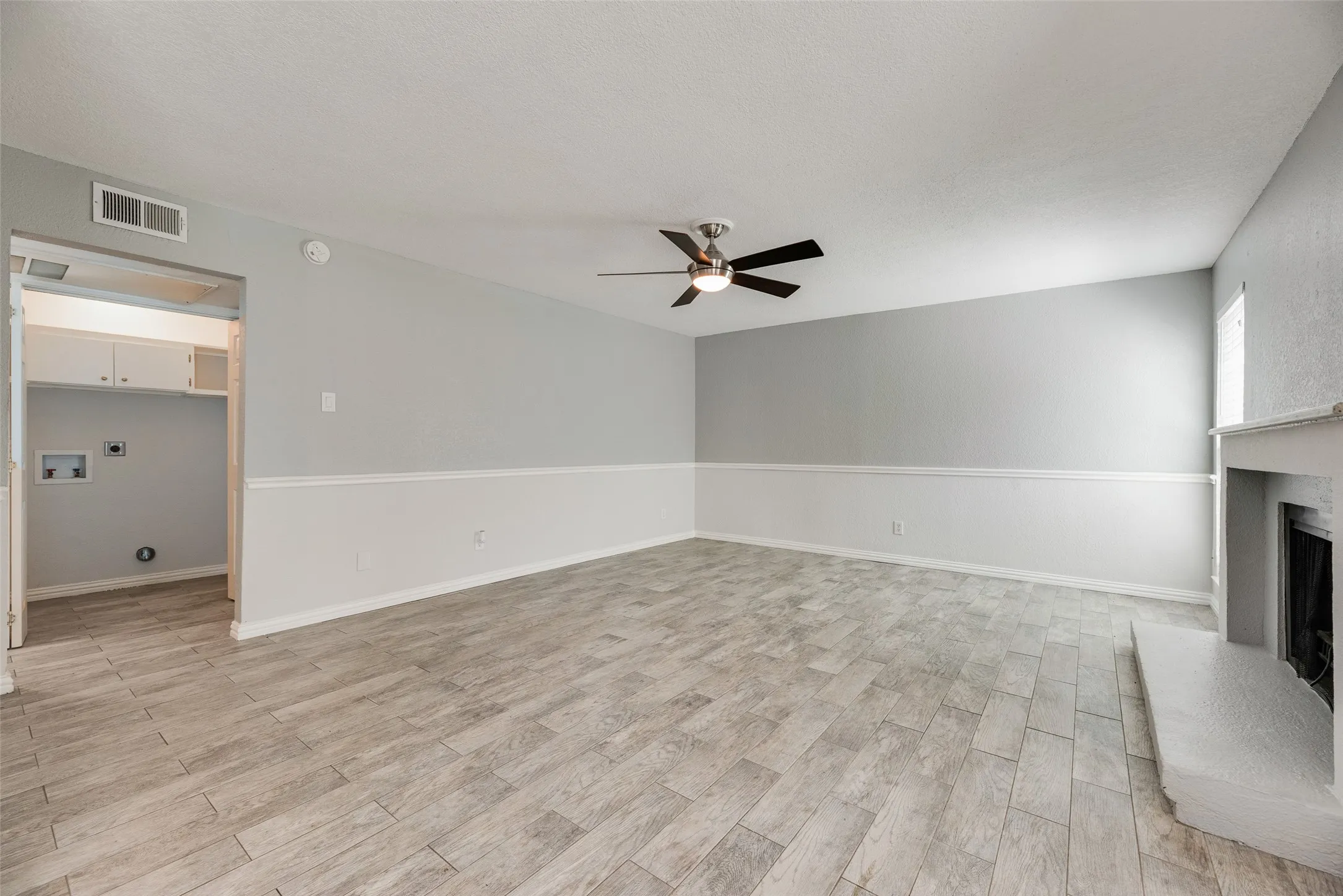 Spacious living area featuring wood-finish flooring, a ceiling fan, and a built-in fireplace
