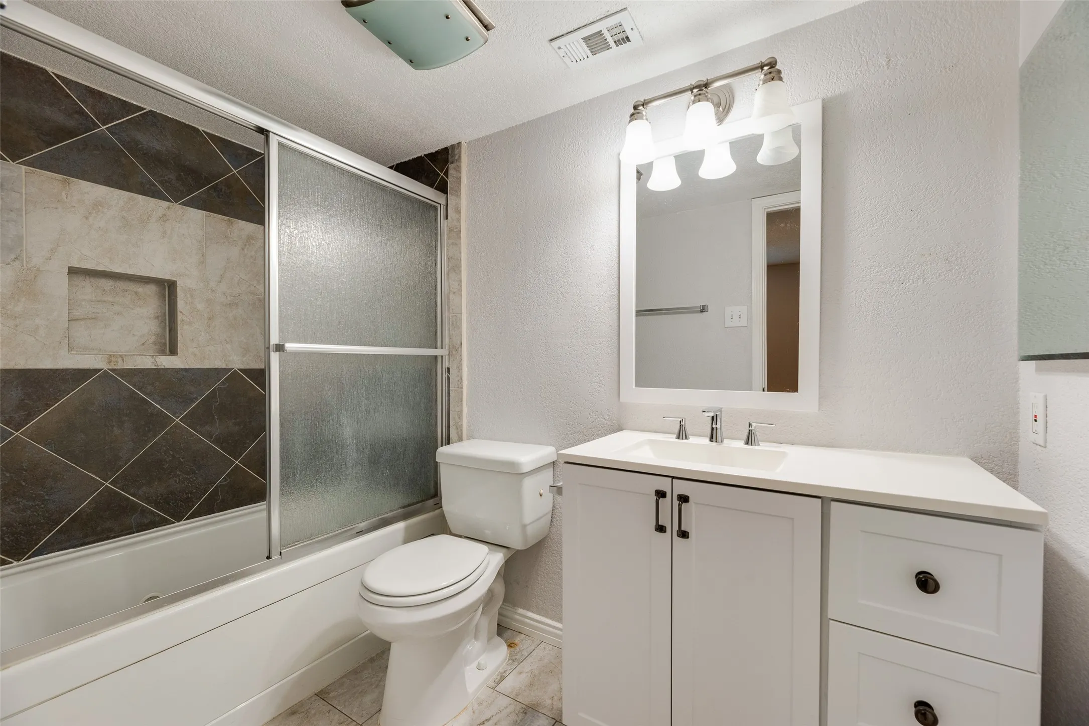 Bathroom featuring a white vanity with a white countertop and rectangular sink, complemented by a mirror with a four-light fixture