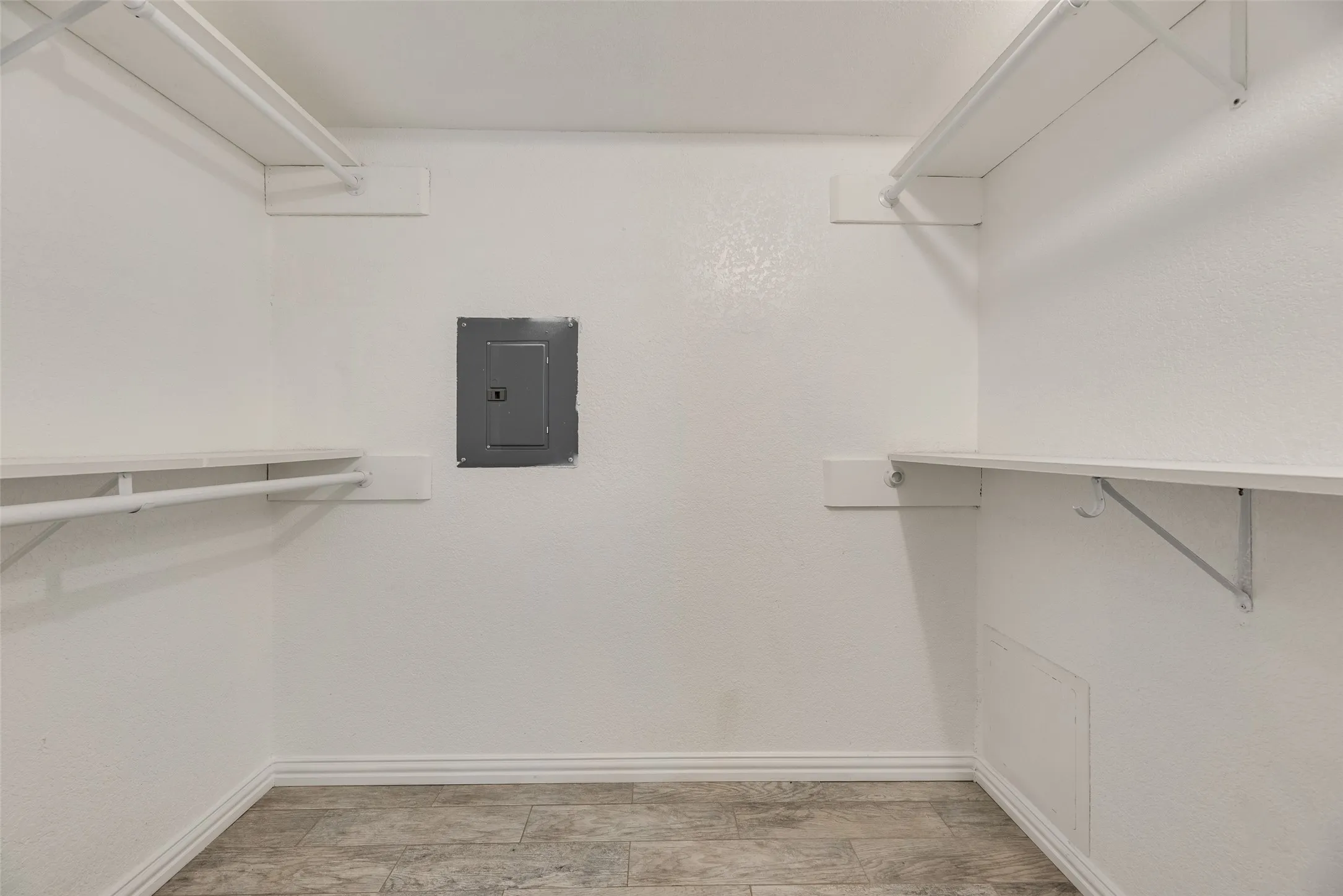 White-painted interior space featuring upper and lower shelving with hanging rods