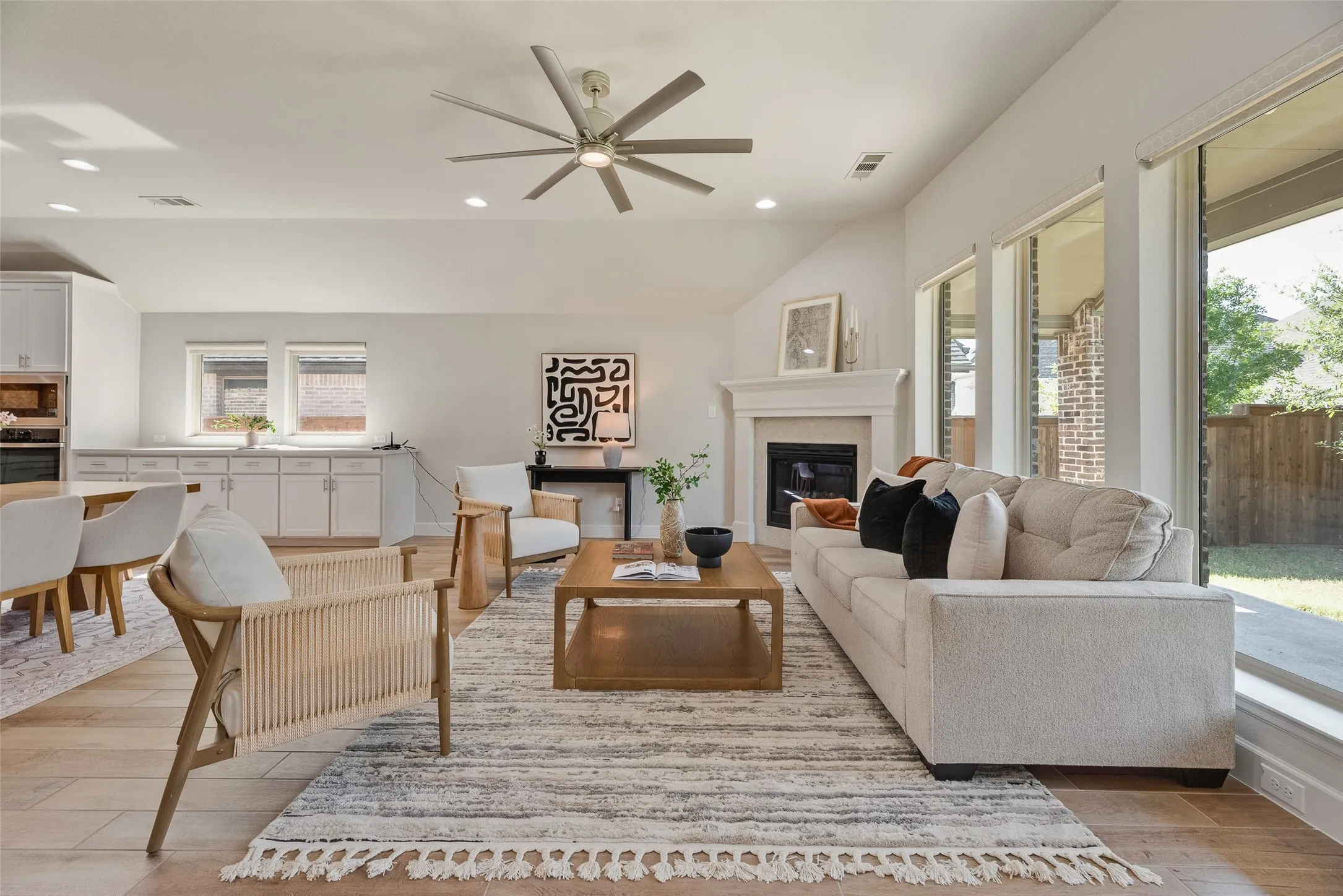 Spacious interior featuring wood-finish flooring, a contemporary ceiling fan, and a fireplace with a classic mantel