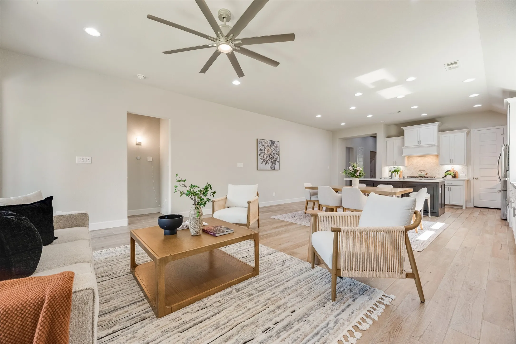 Open-concept living space featuring light-toned wood-finish flooring, recessed lighting, and a modern ceiling fan
