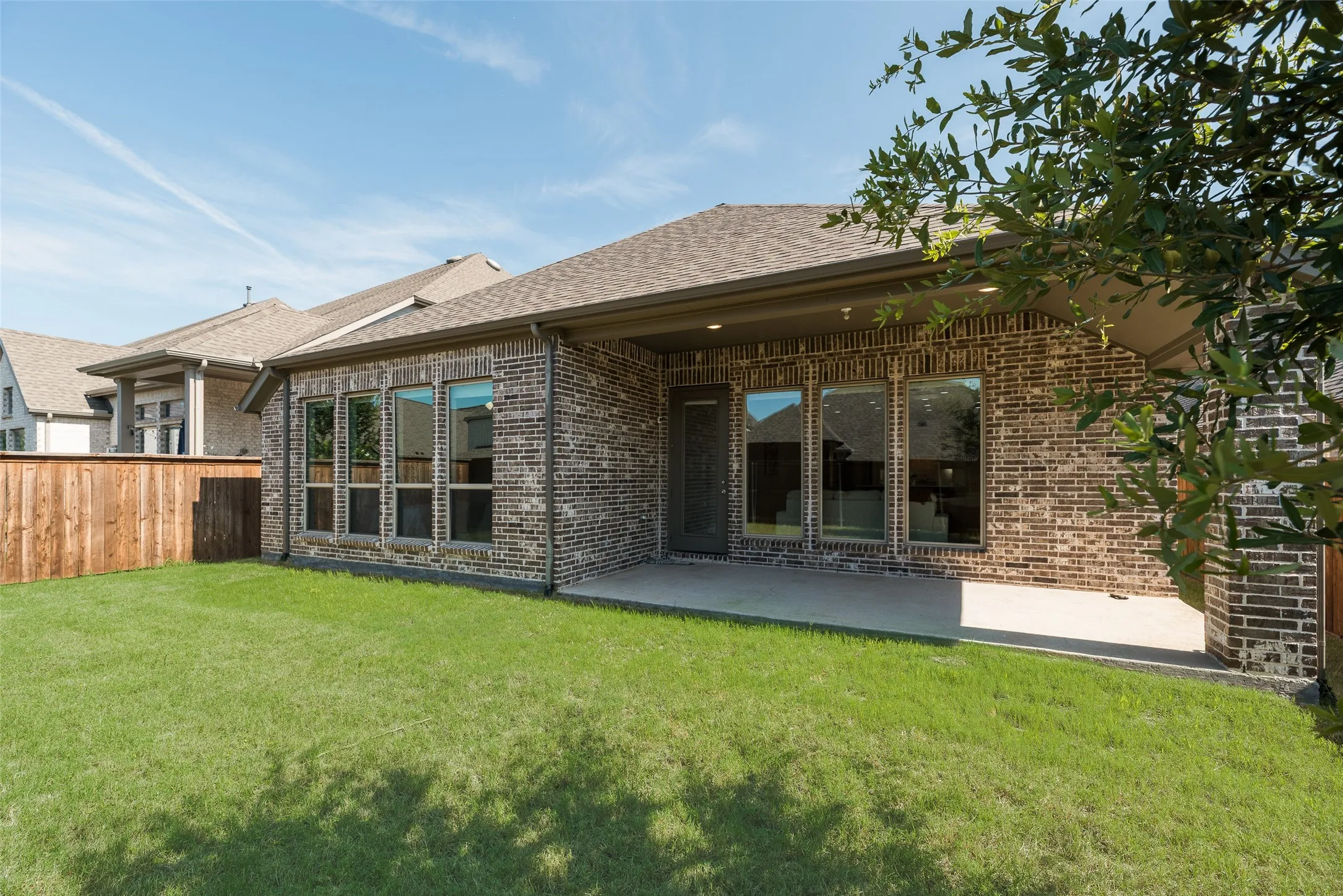 Expansive backyard featuring a manicured lawn, a large concrete patio, and a privacy fence