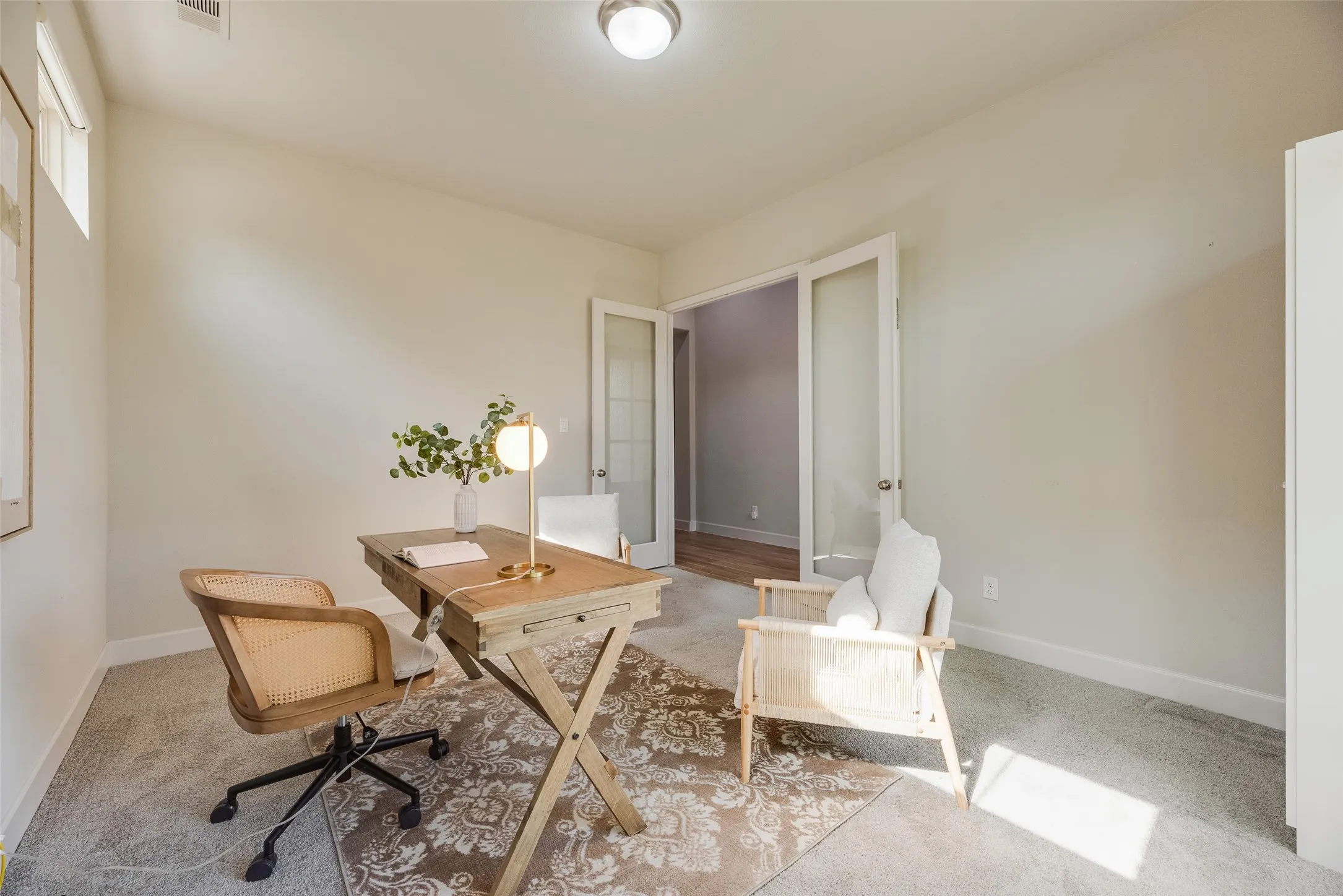Bright interior space featuring light gray carpeting, neutral wall paint, and white trim