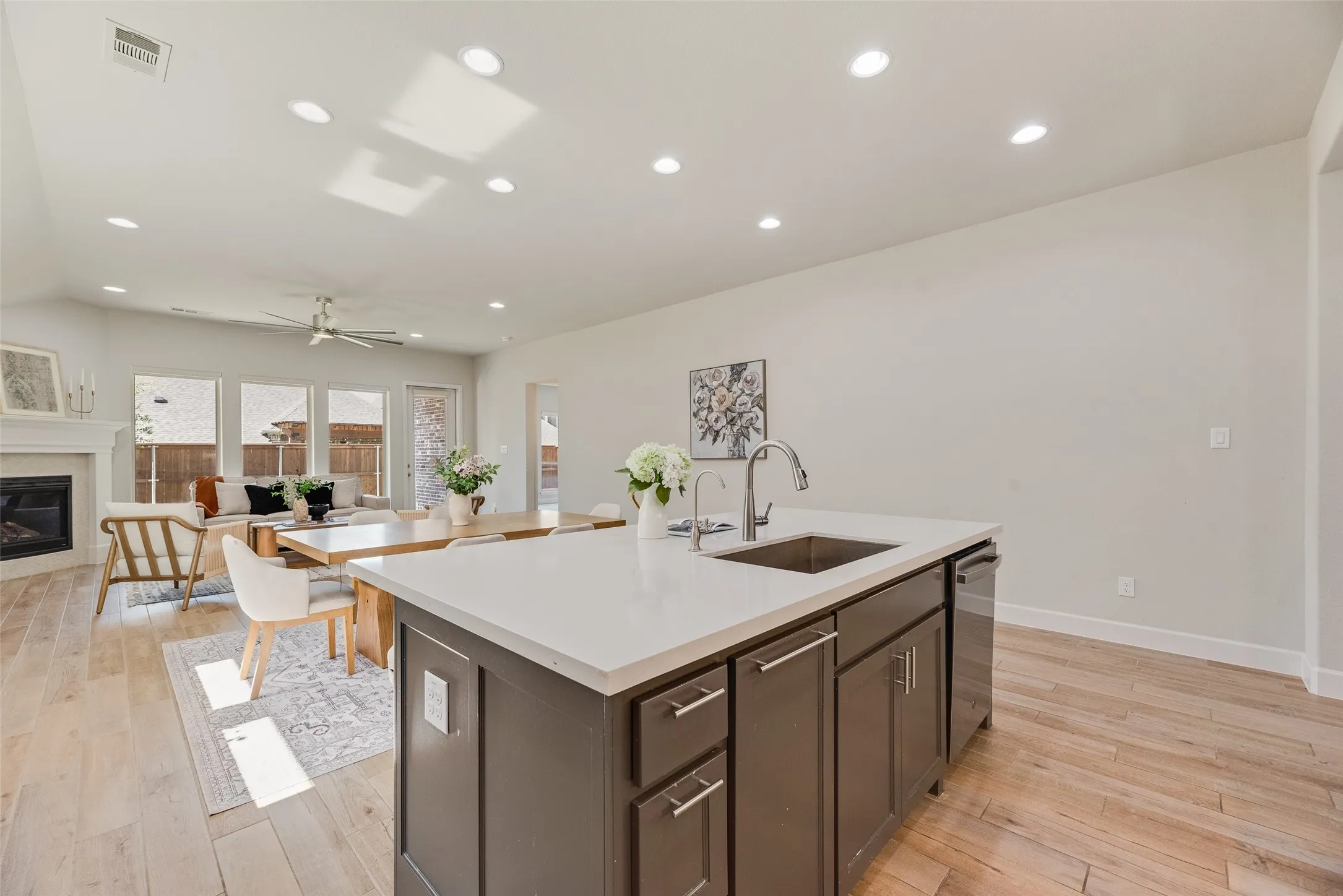 Kitchen island with a light-toned countertop, integrated sink, and dark cabinetry