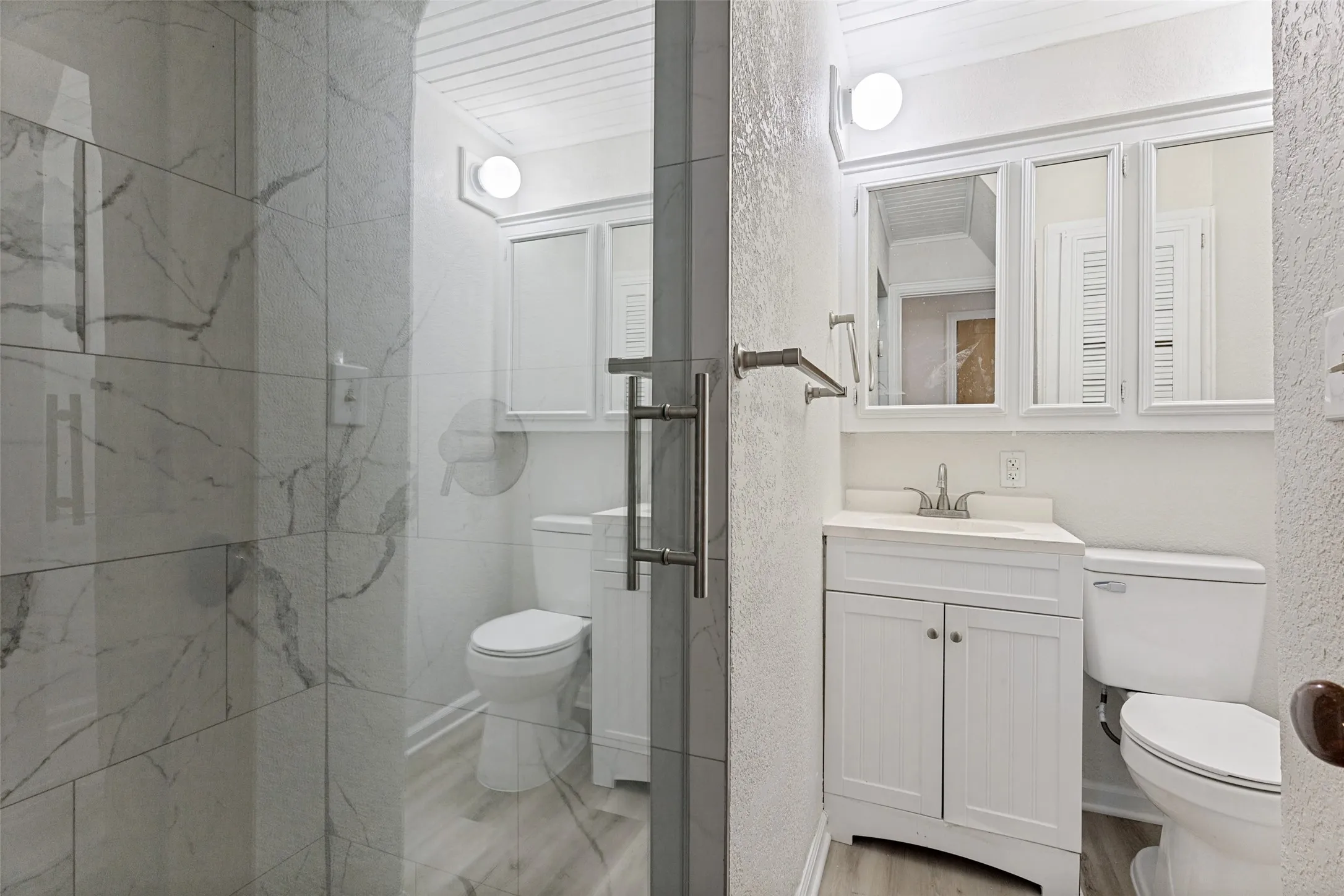 Shower enclosure with large format stone-look tiles and a glass door