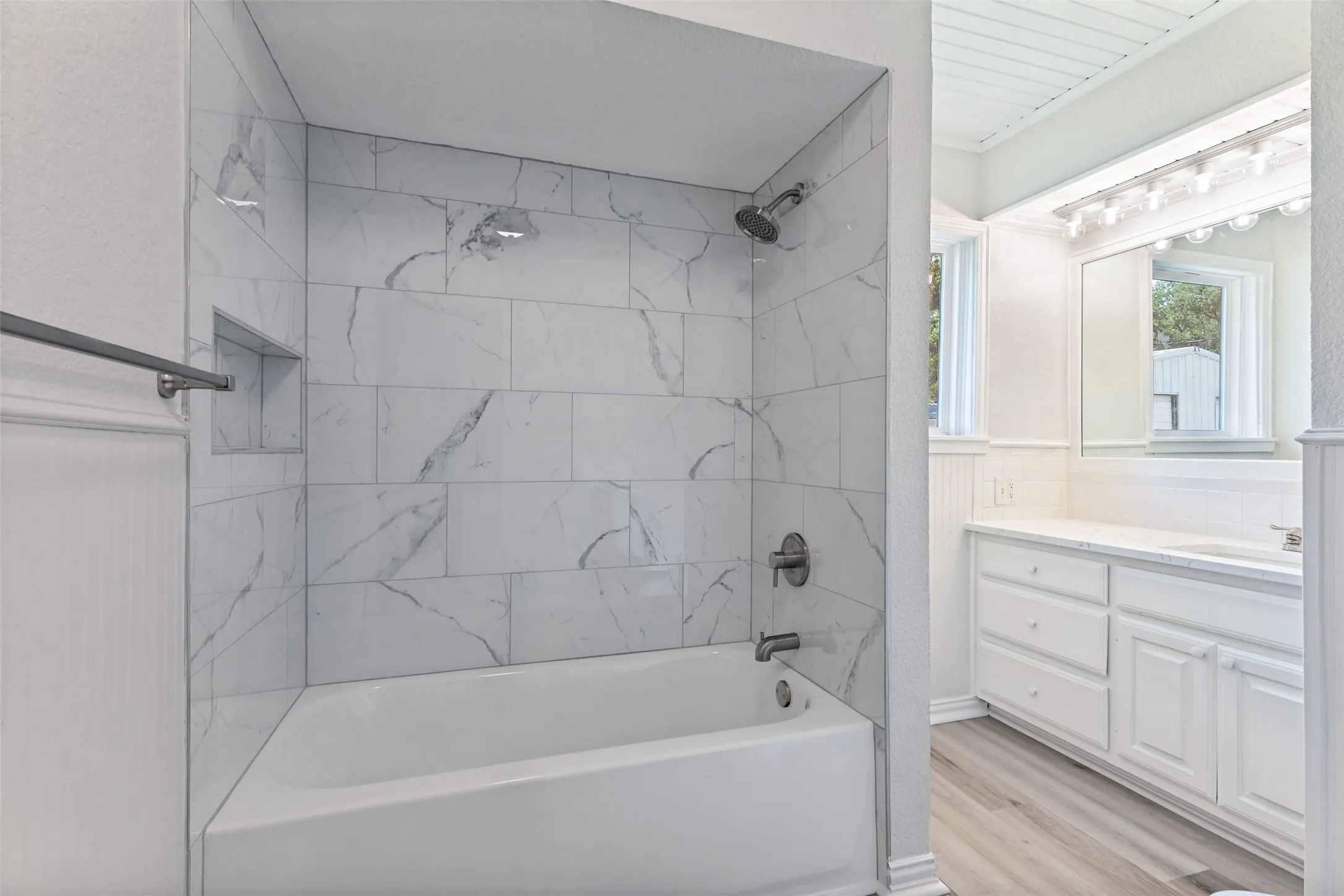 Bathroom featuring a tiled shower/tub combination with a recessed niche and dark-toned fixtures