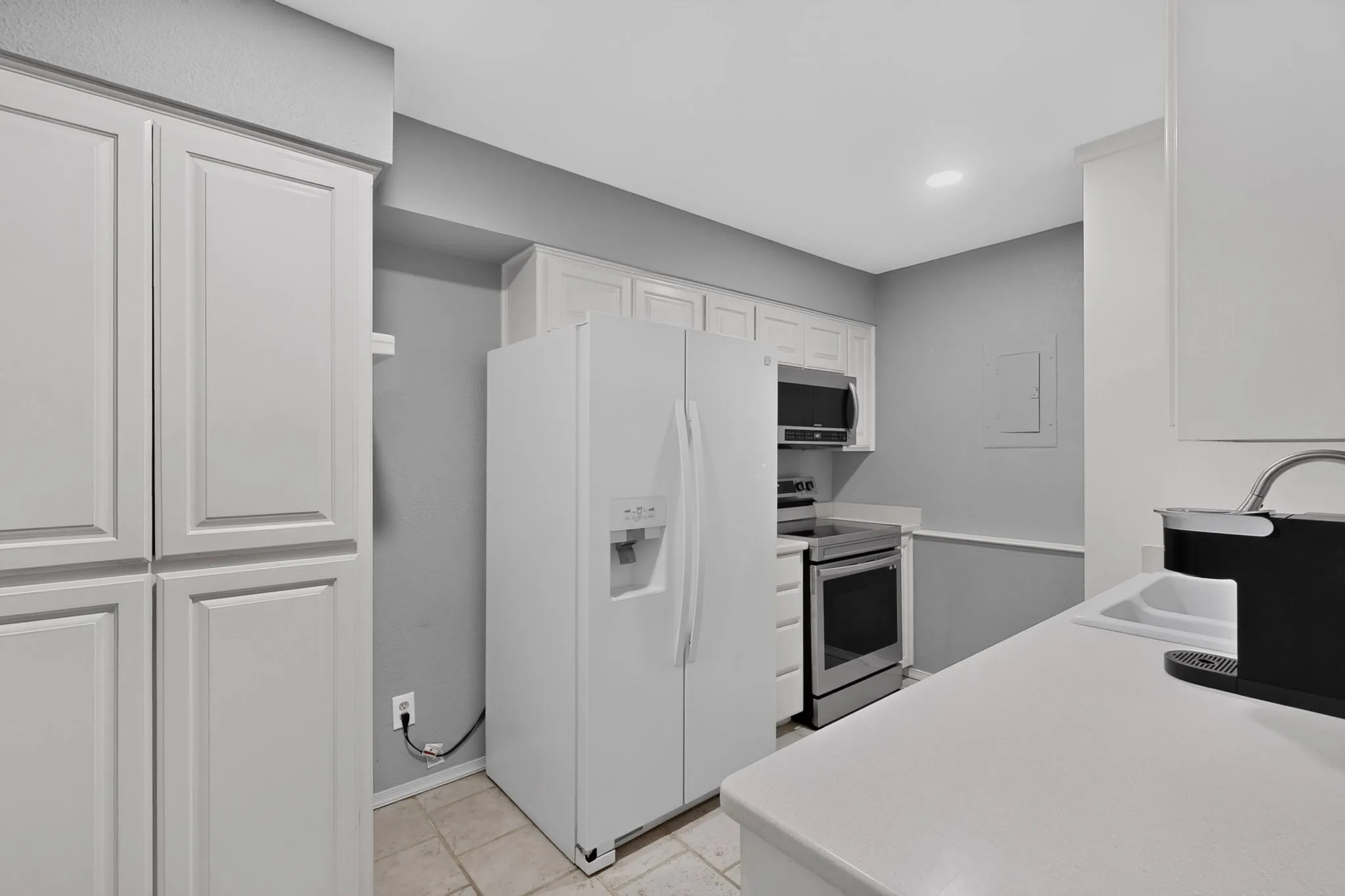 Kitchen featuring white cabinetry, white countertops, tile flooring, and stainless steel appliances