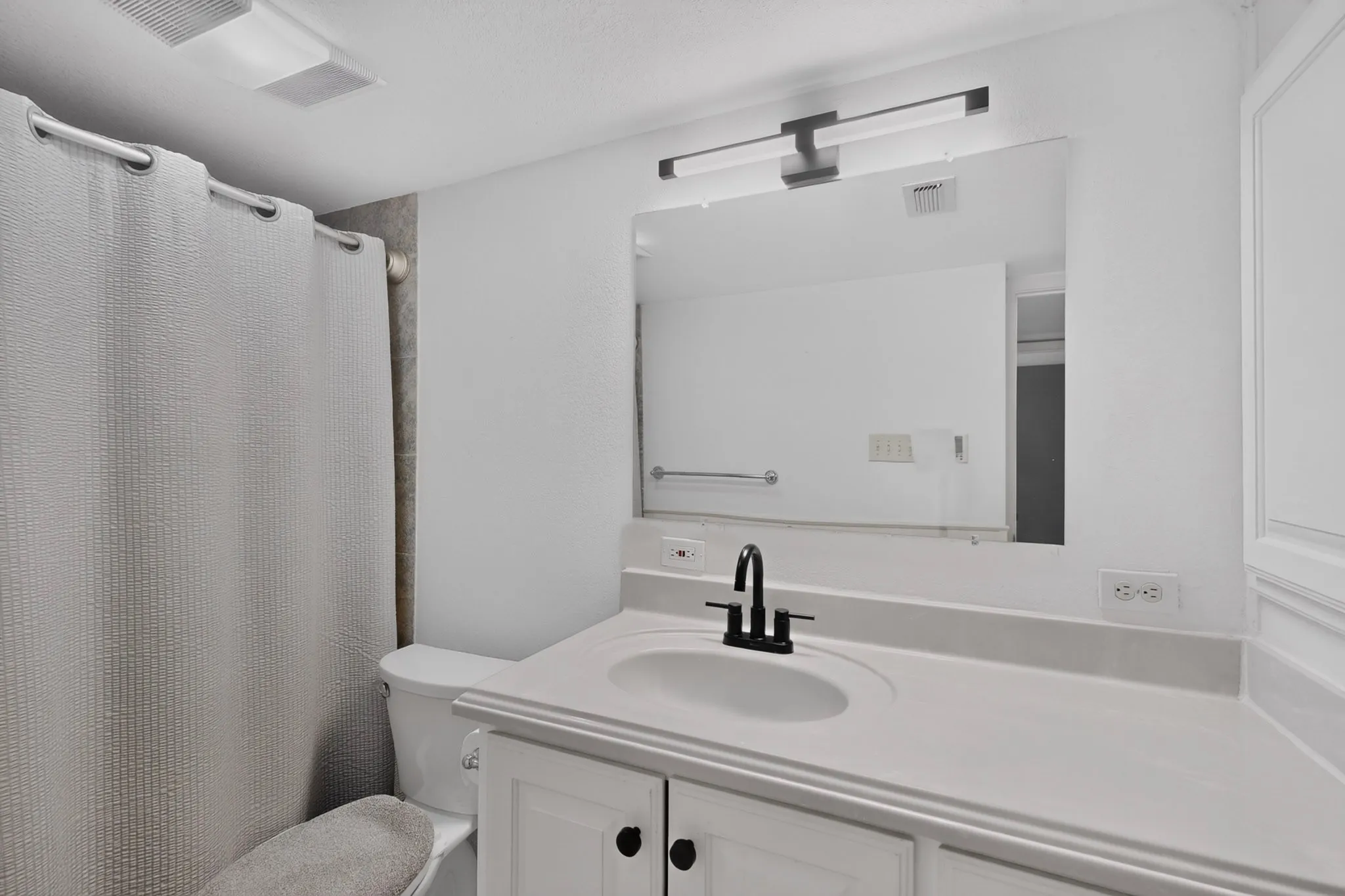 Bathroom featuring a white vanity with an integrated sink, matte black faucet, and a large rectangular mirror