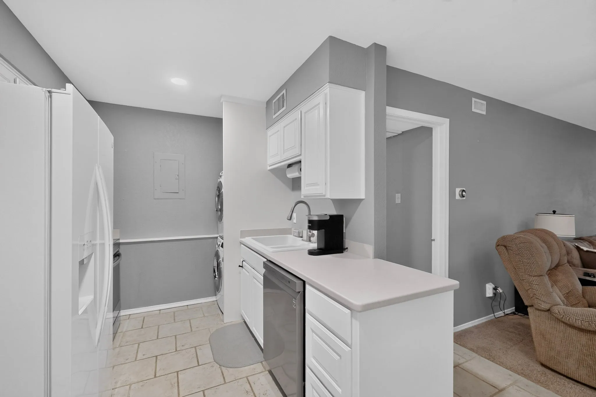 Kitchen with white cabinetry, stainless steel dishwasher, and a white sink