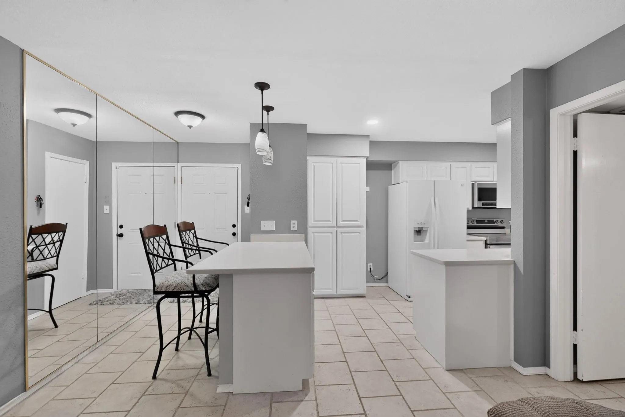 Kitchen area featuring white cabinetry, integrated appliances, and a breakfast bar with pendant lighting