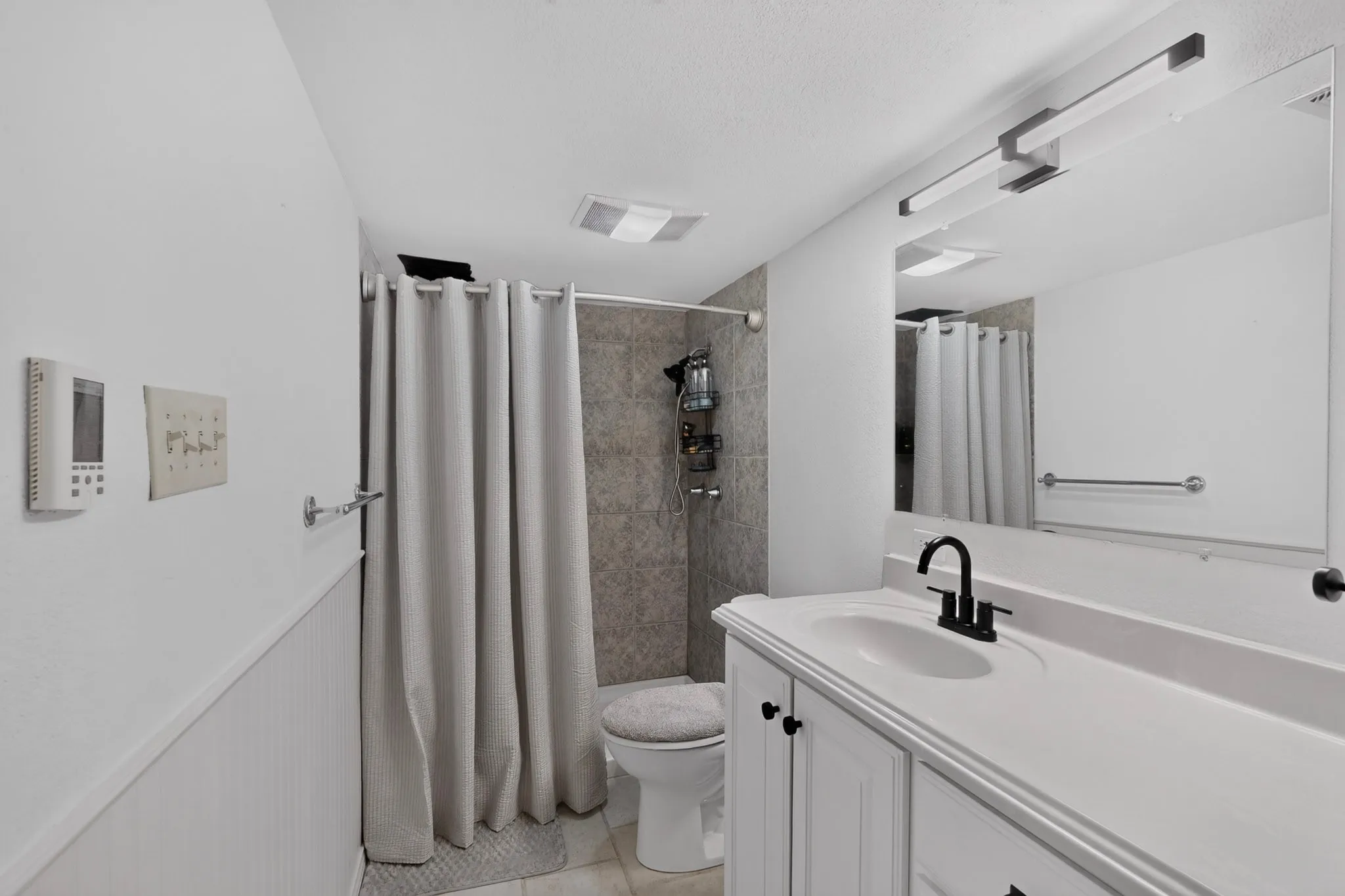 White vanity with integrated sink, black faucet, and rectangular mirror