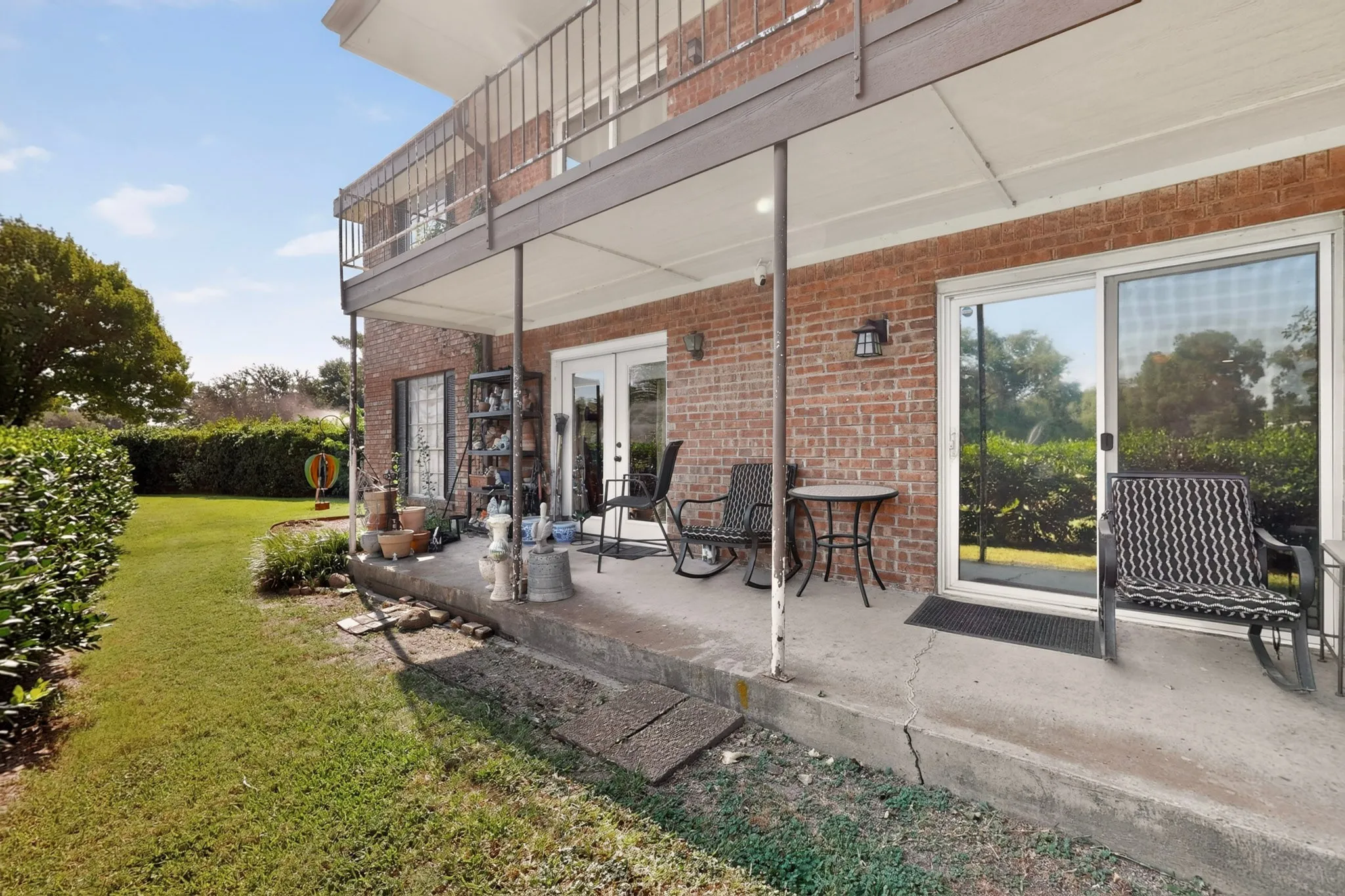 Brick exterior featuring a ground-level patio, an upper-level balcony, a sliding glass door, and a double French door