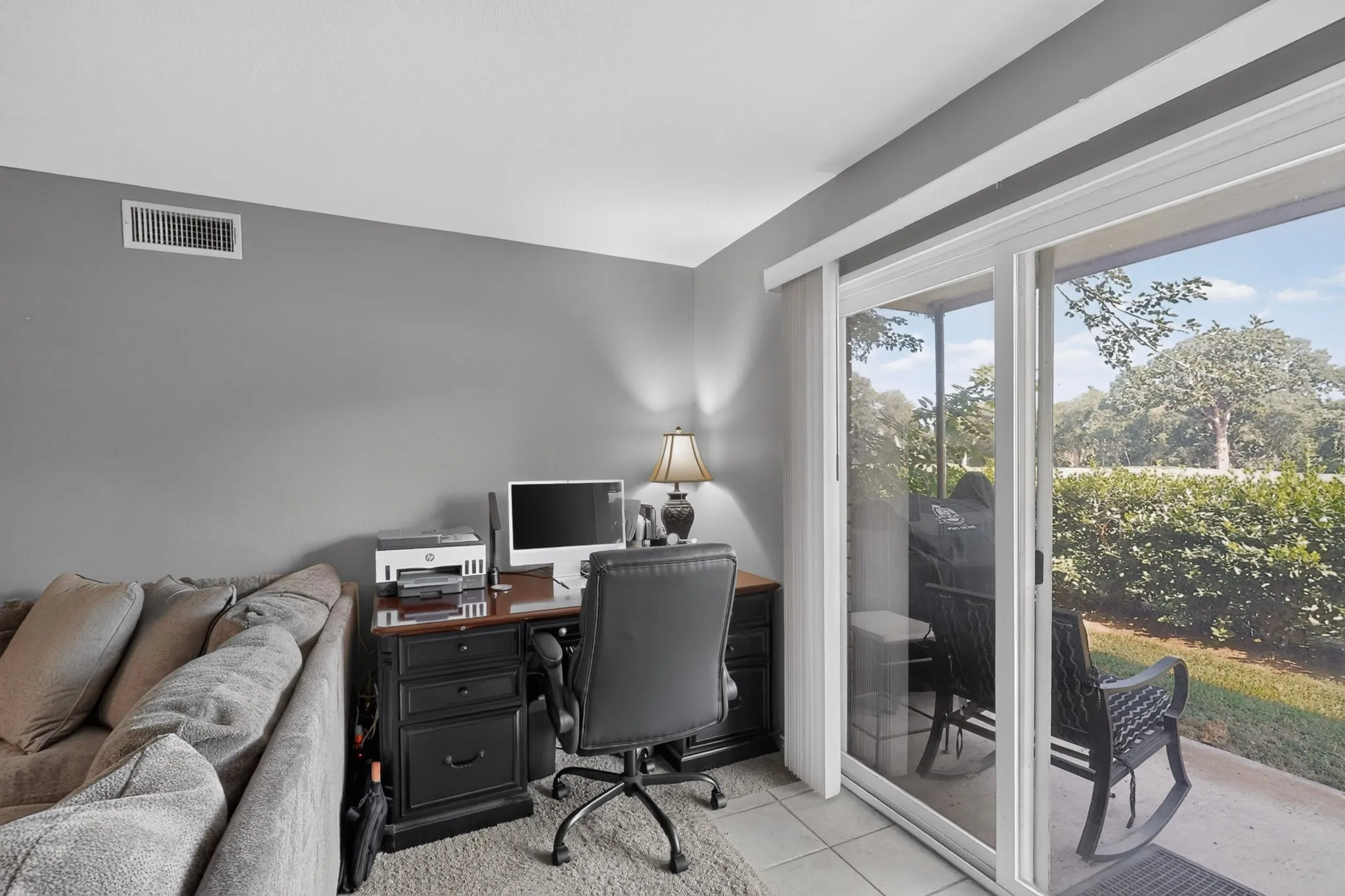 Sliding glass doors opening to a private patio, featuring tiled flooring, a gray accent wall, and an air conditioning vent