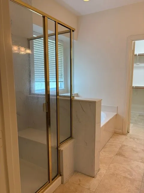Glass-enclosed shower with a gold-tone frame and built-in bench