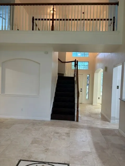 Two-story entryway featuring a dark wood-finish staircase with white balusters and a wood-finish handrail