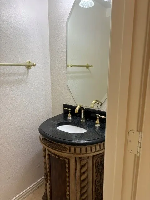 Ornate vanity with carved details, dark countertop, and brass-tone fixtures