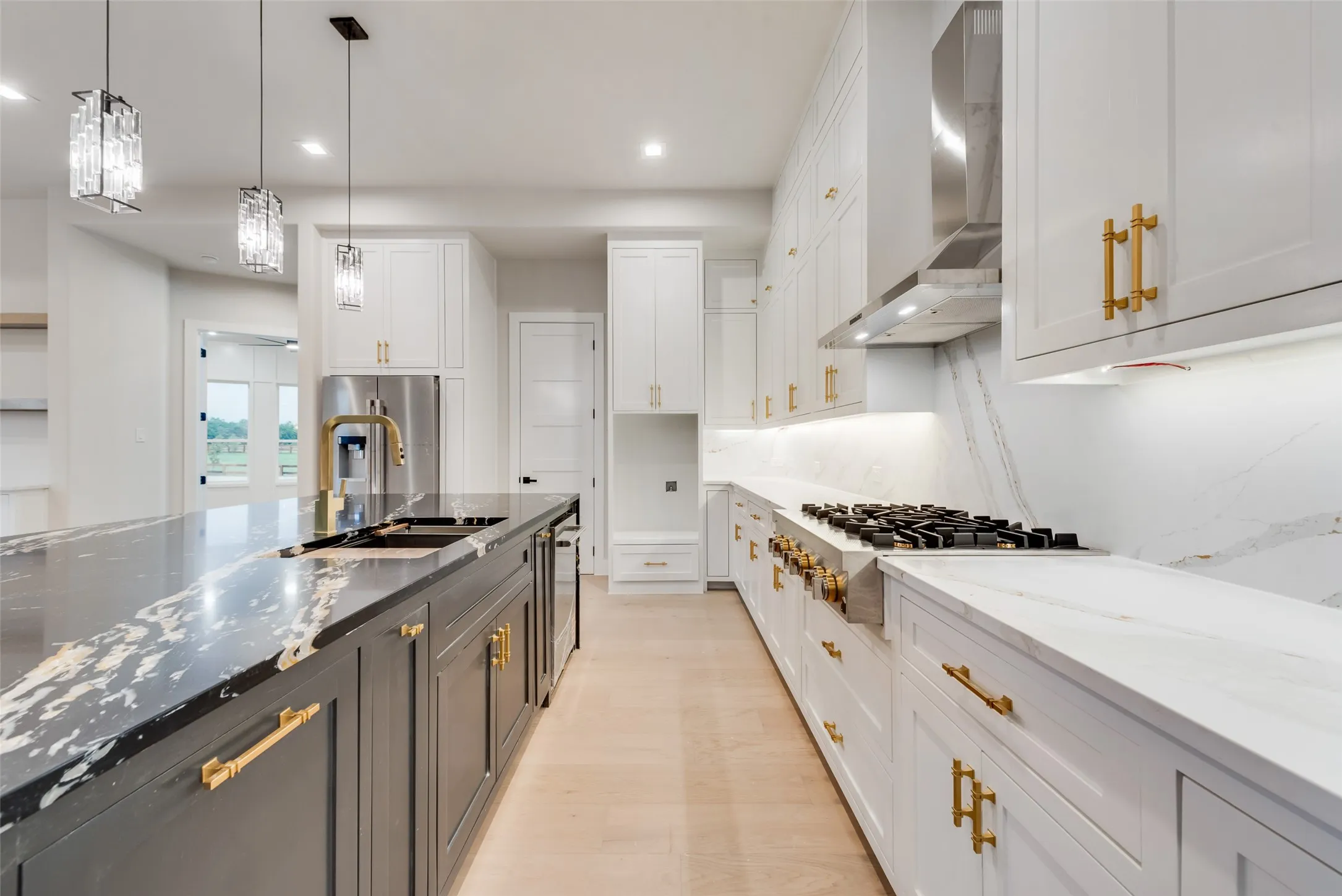 Gourmet kitchen featuring a large island with dark stone countertops, stainless steel appliances, and light wood-finish flooring