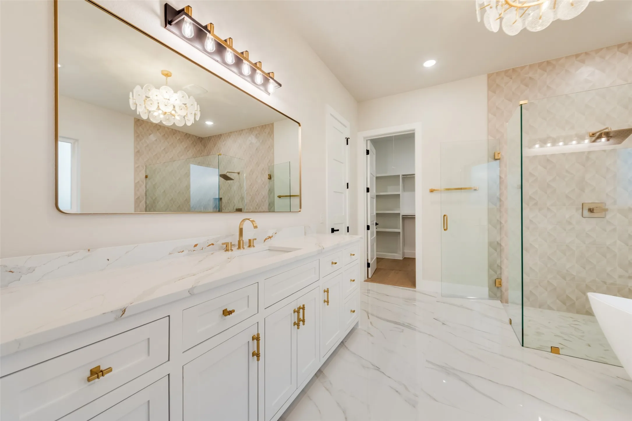 Spacious bathroom featuring a double vanity with white cabinetry and a white countertop, a large rectangular mirror, a glass-enclosed shower with tiled walls, and white marble-look flooring
