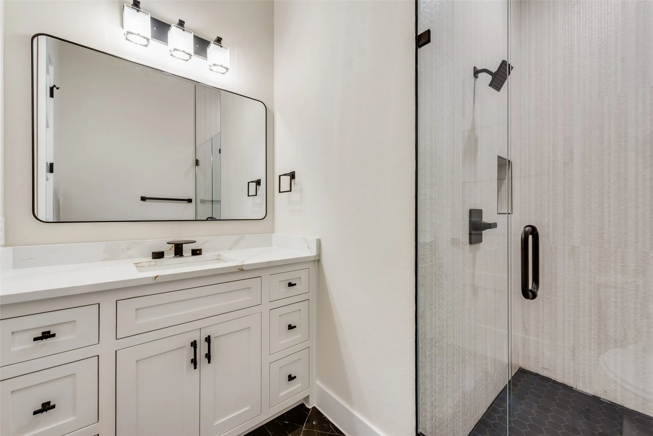 Bathroom featuring a white vanity with shaker-style cabinetry, a white countertop with an integrated sink, and a framed mirror with overhead lighting