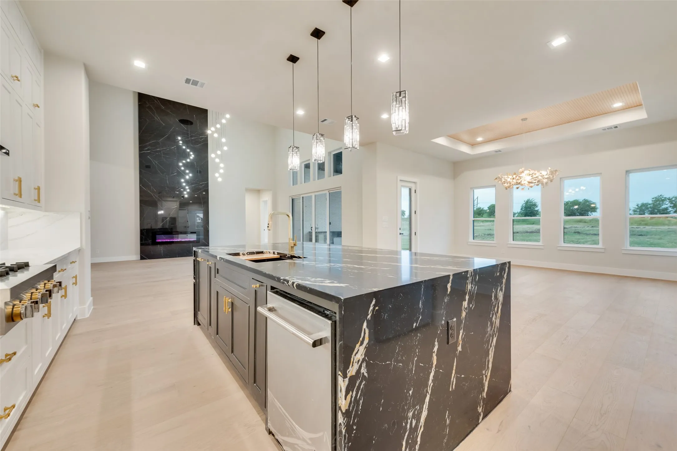 Spacious open-concept living area featuring a large kitchen island with a dark, veined countertop, stainless steel appliances, and pendant lighting