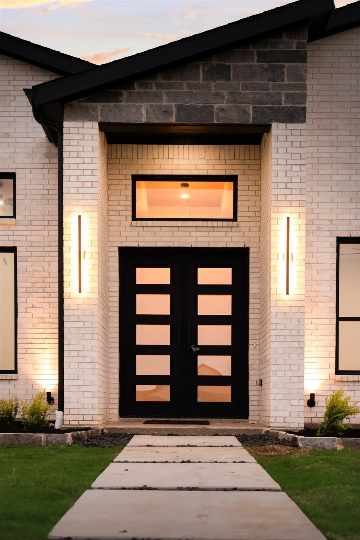 Modern facade featuring a prominent double-door entry with rectangular lites, complemented by linear sconces