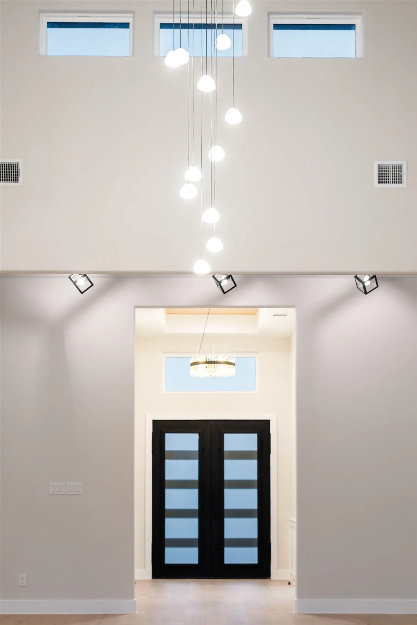 Two-story entryway featuring a multi-pendant chandelier and light wood-finish flooring