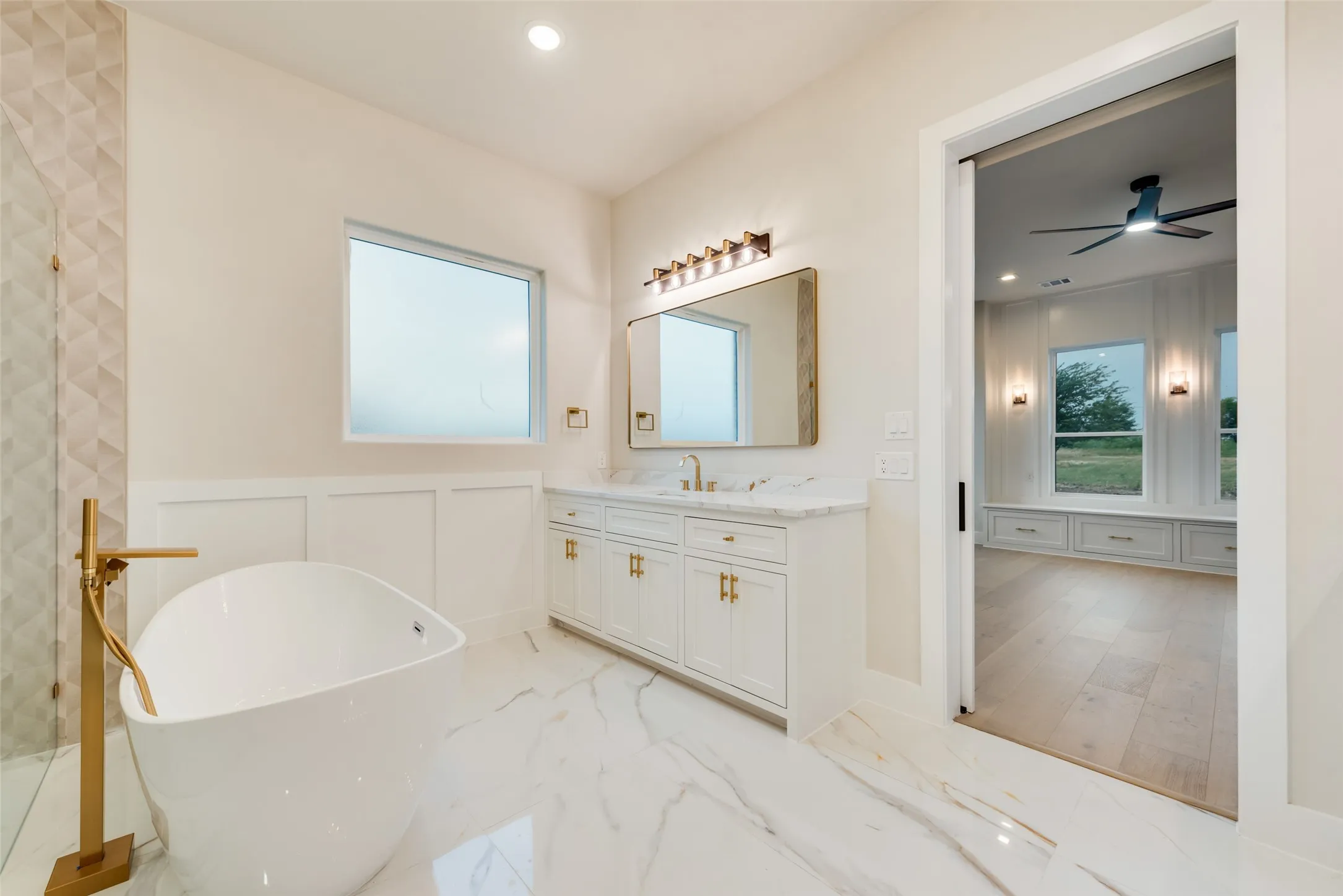 Freestanding soaking tub with a gold-tone floor-mounted faucet