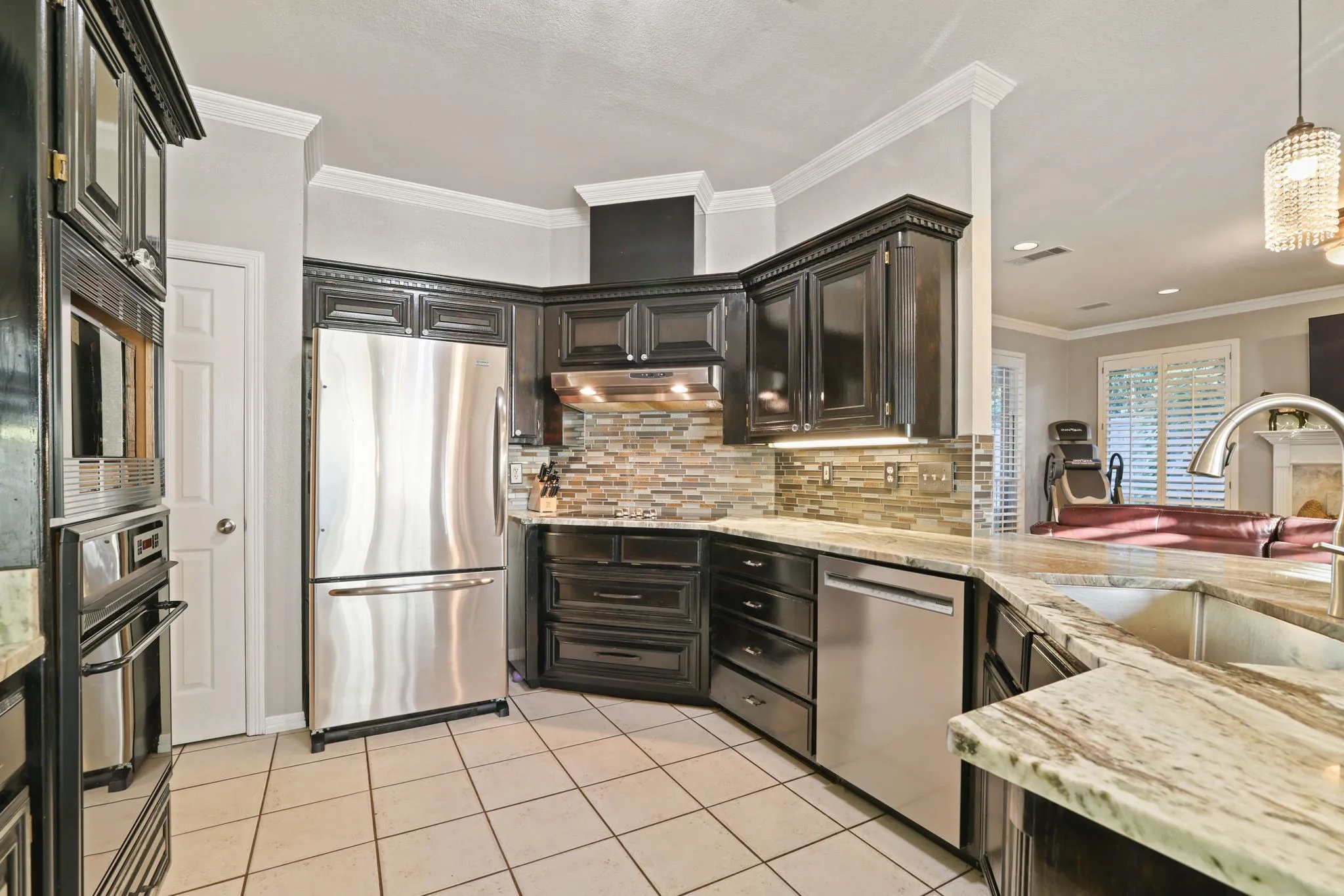 Modern kitchen featuring dark wood cabinetry, stainless steel appliances, and light-toned tile flooring