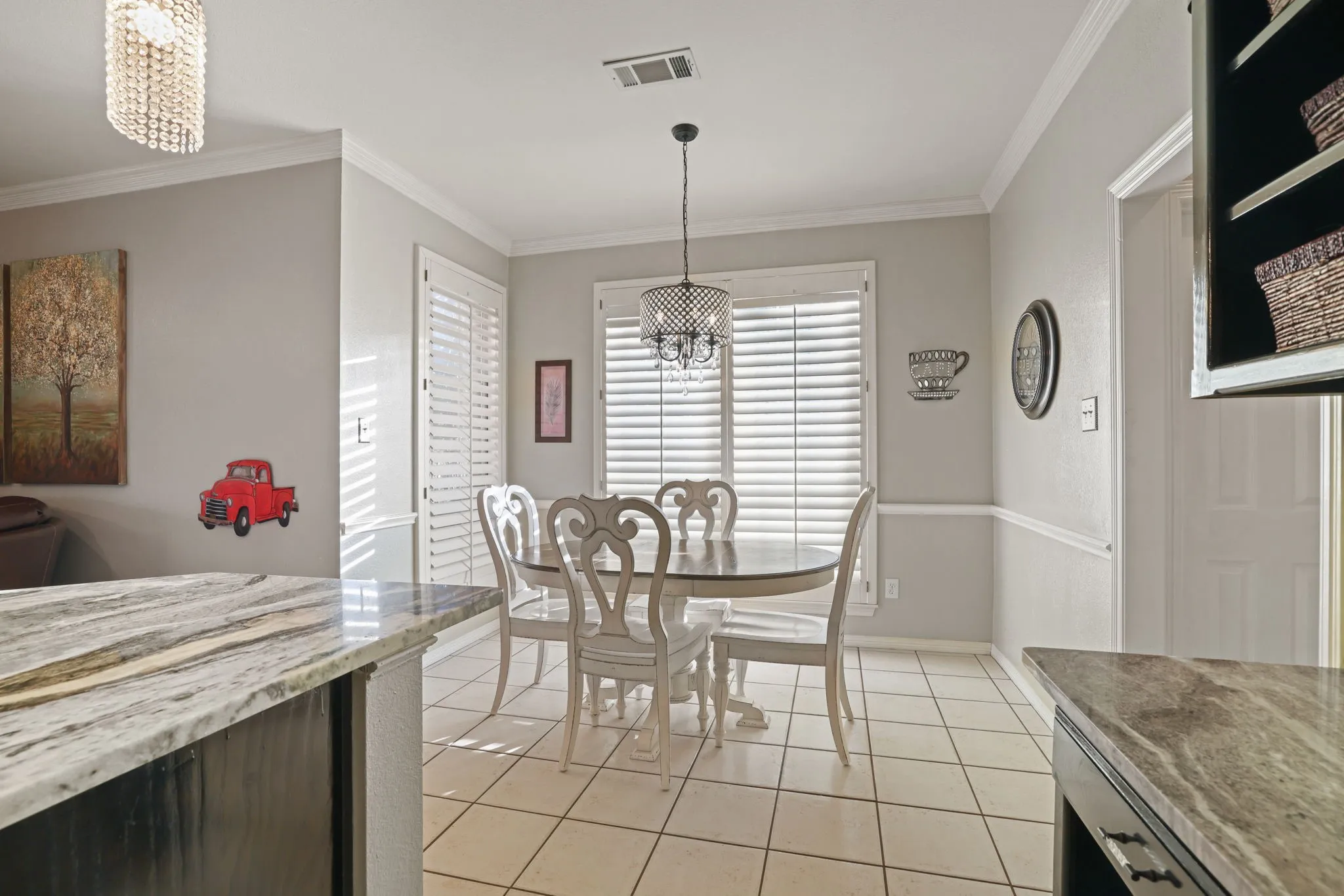 Dining area featuring white plantation shutters, a decorative chandelier, and tile flooring