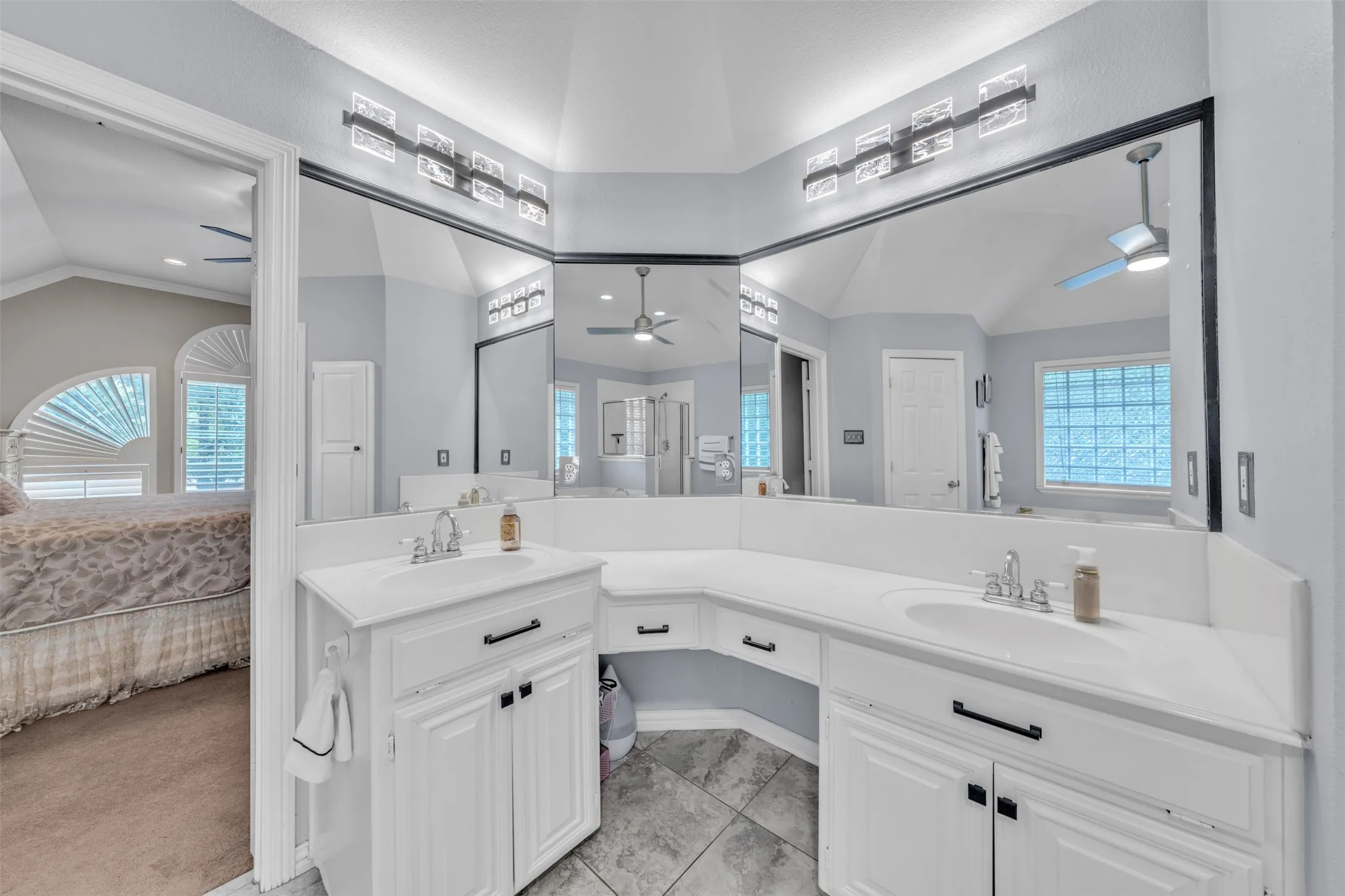 Dual vanity with white cabinetry and integrated sinks, extensive countertop space, and a large wall-mounted mirror