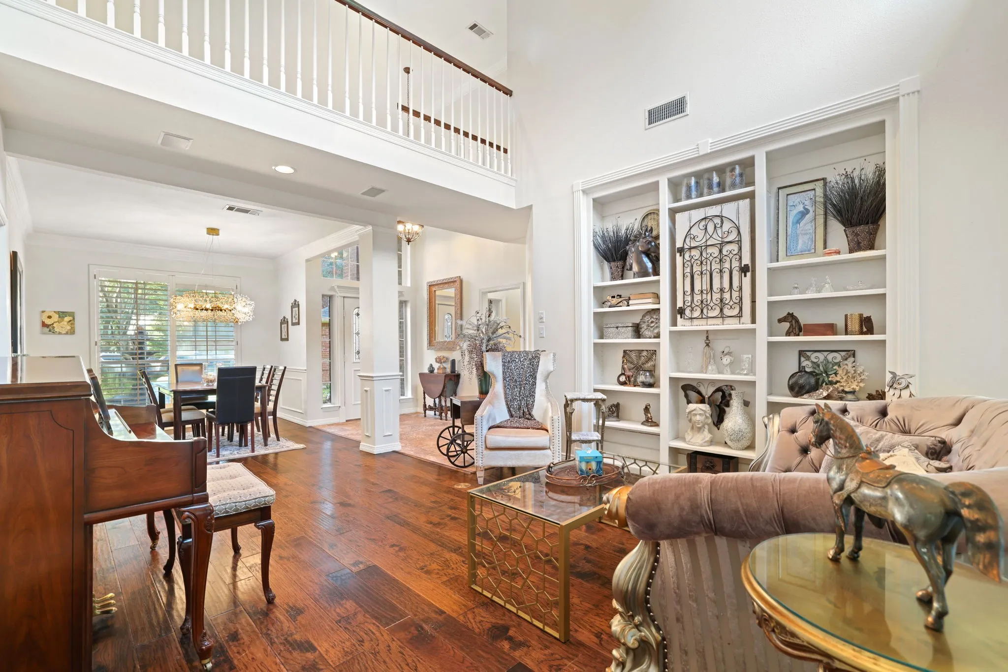 Living area featuring high ceilings, rich wood-finish flooring, built-in shelving, and a second-story interior balcony
