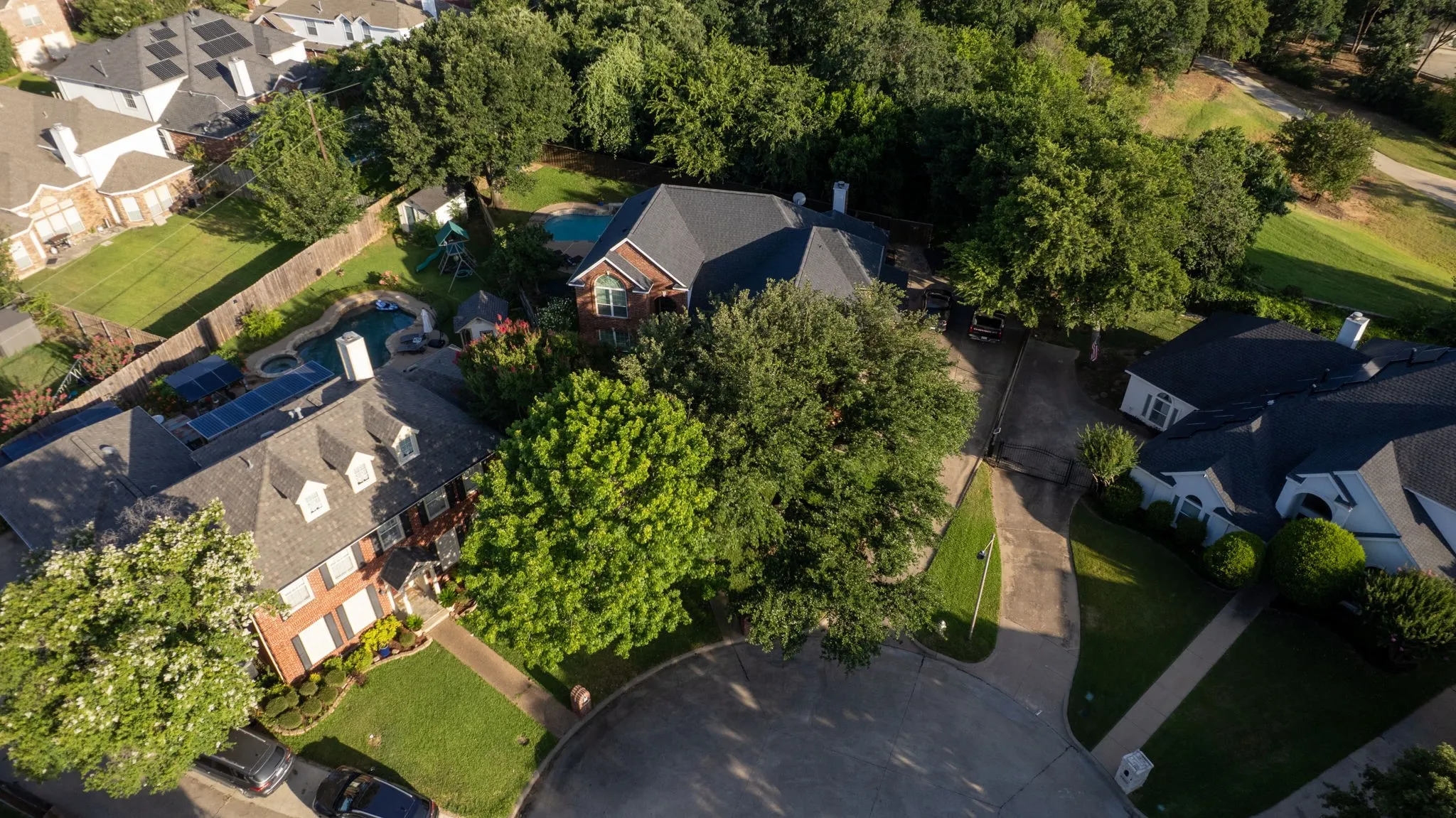 Aerial perspective showcasing a residential property with a dark shingle roof and brick exterior