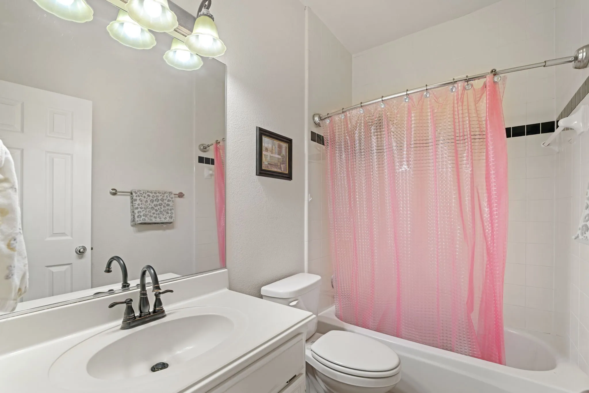 Bathroom featuring a white vanity with an integrated sink, a dark bronze-finish faucet, and a large mirror