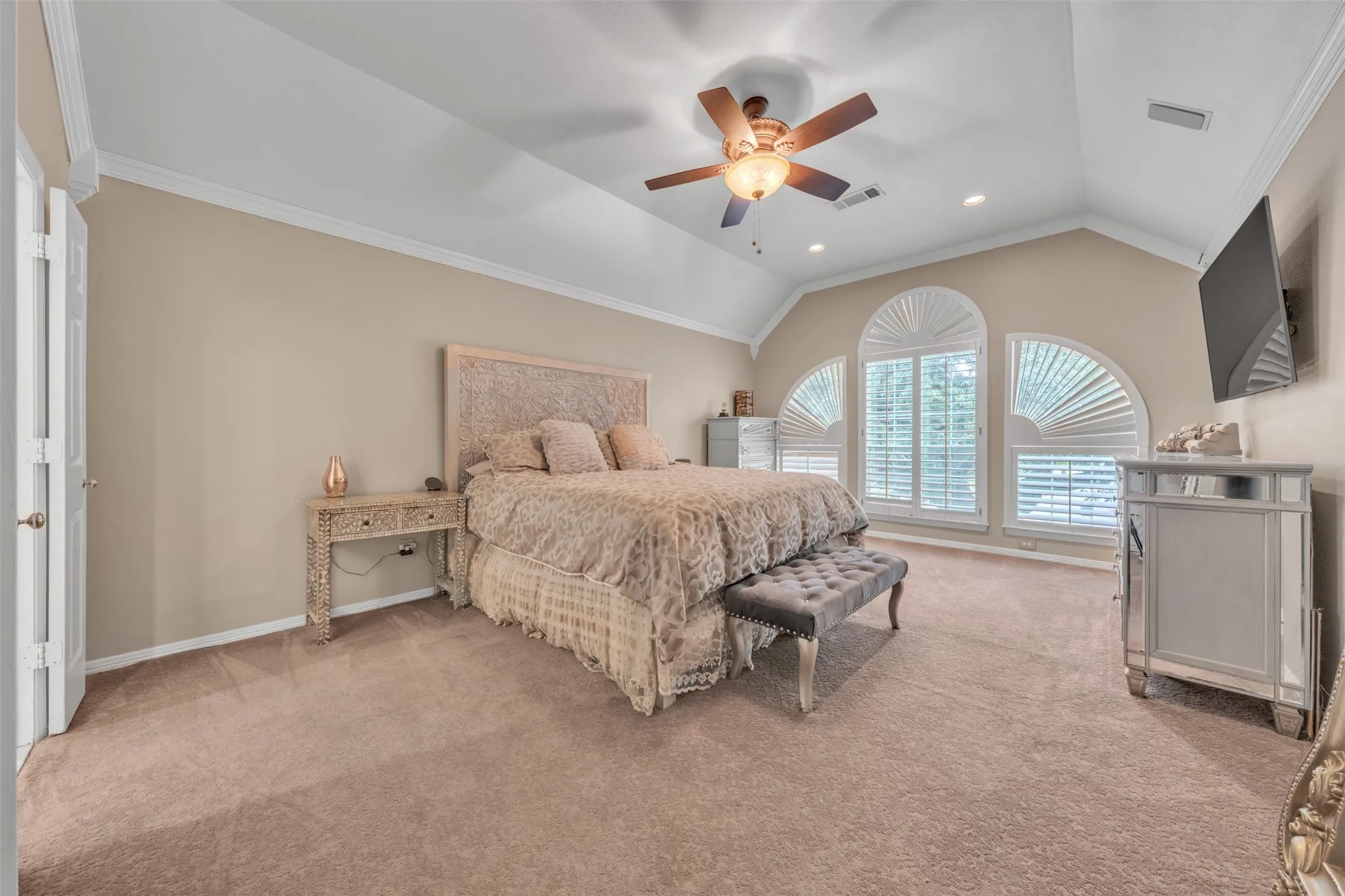 Vaulted ceiling with a ceiling fan, arched windows, plantation shutters, recessed lighting, and neutral carpeting