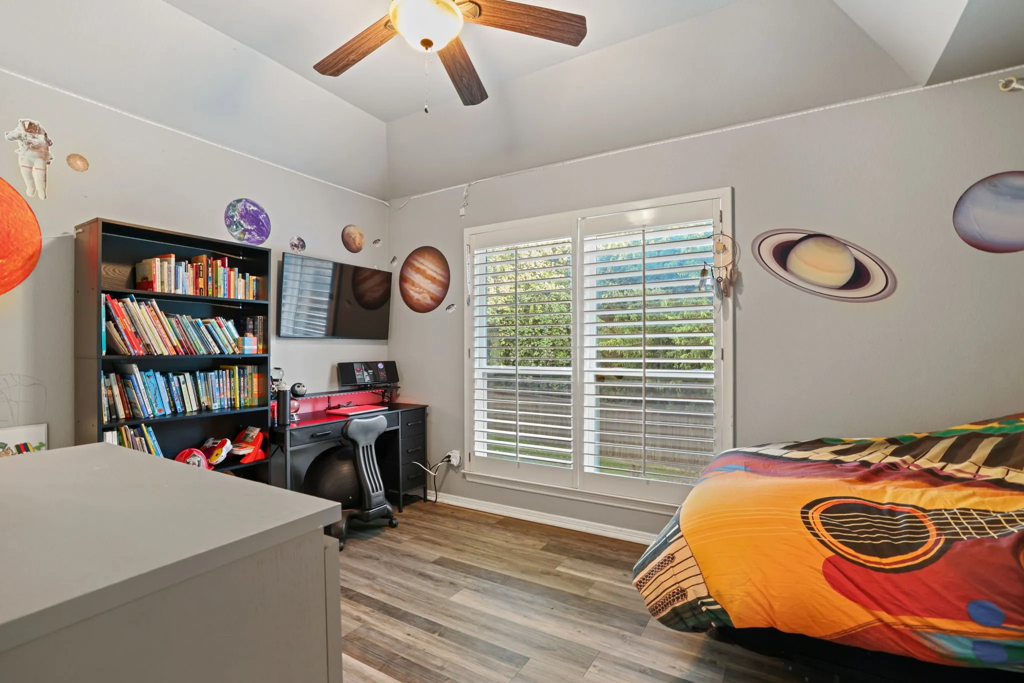 Vaulted ceiling room featuring wood-finish flooring and a ceiling fan with integrated lighting