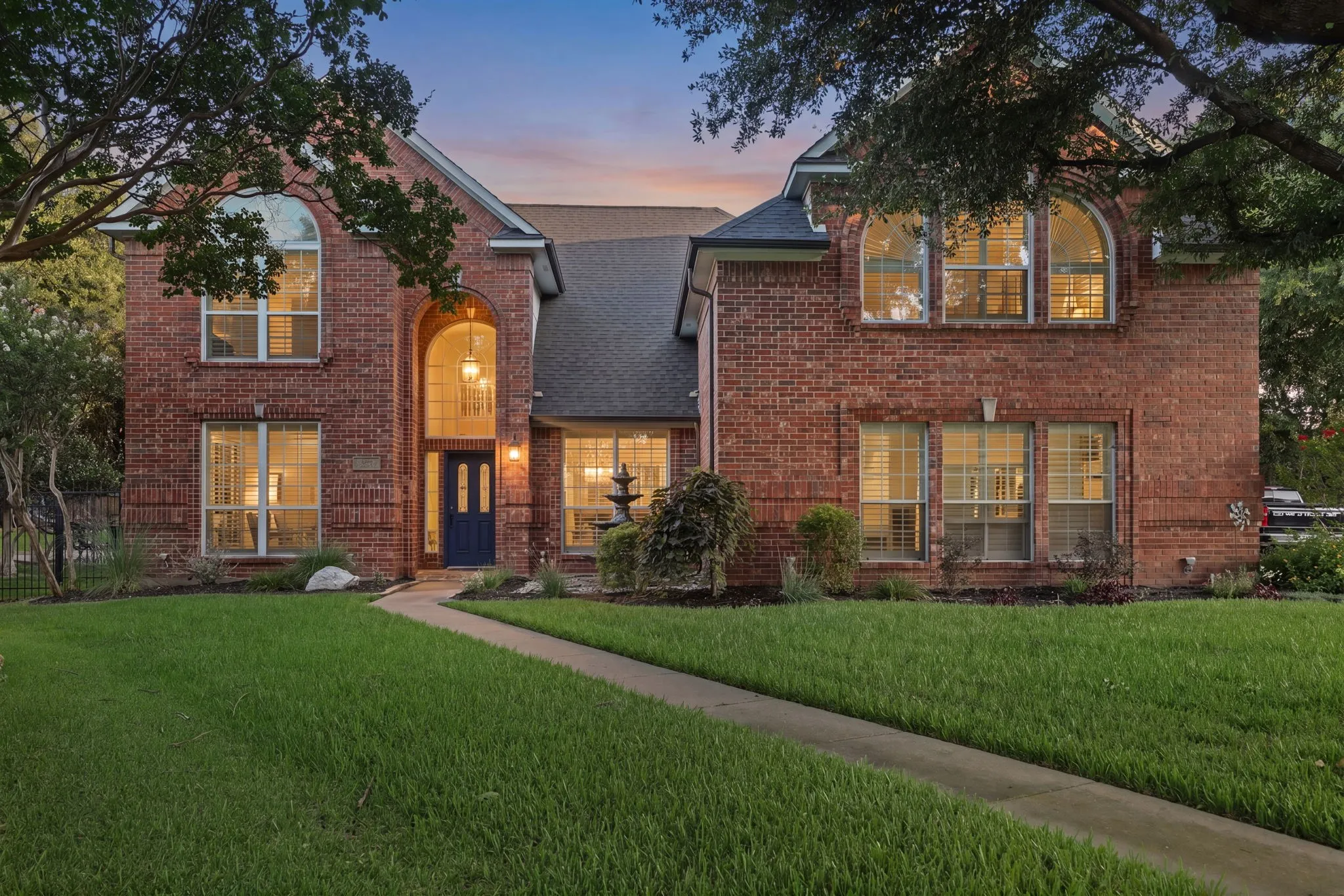 Brick facade residence featuring a prominent entryway with an arched portico and dark blue door