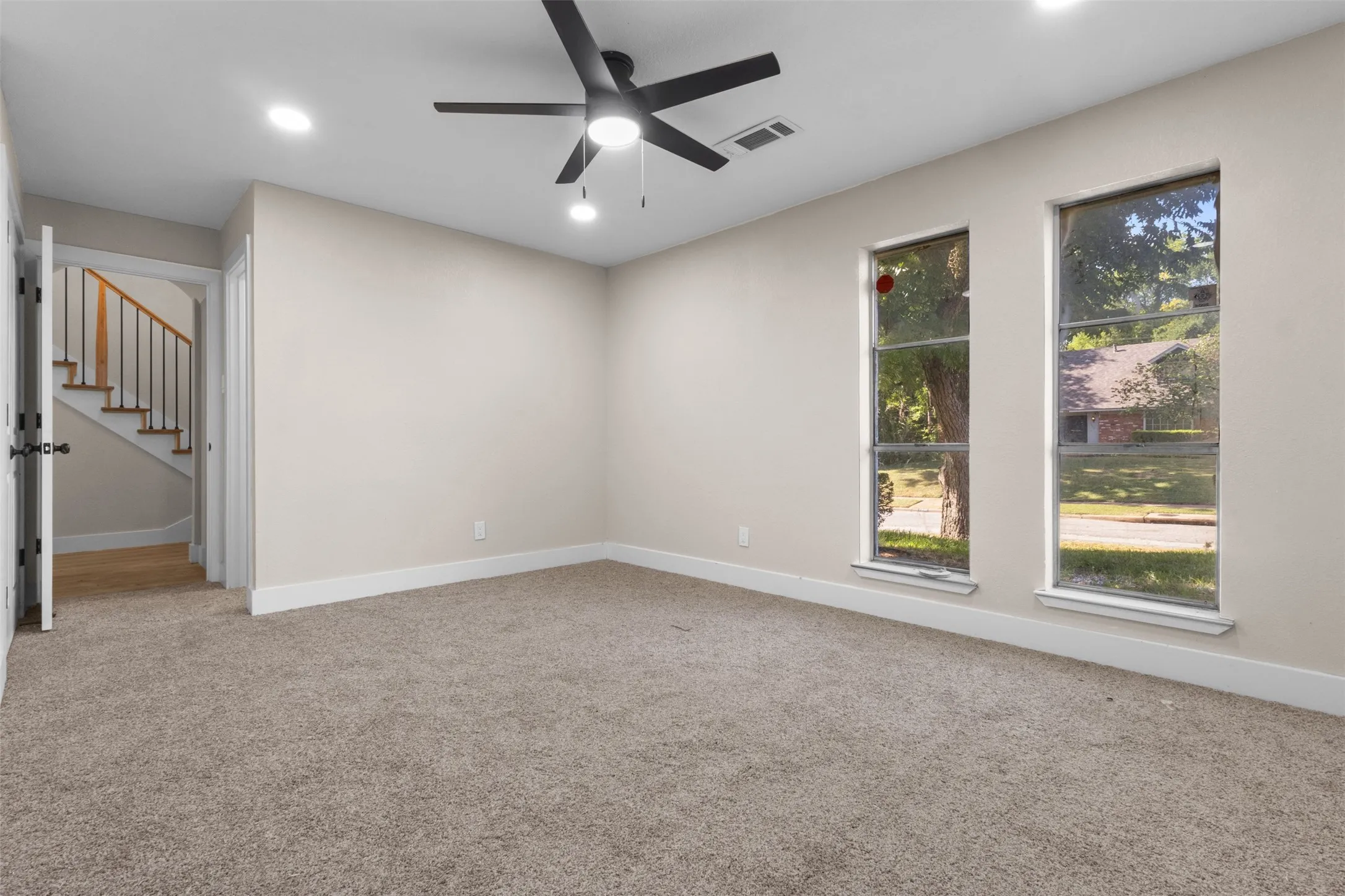 Carpeted room featuring a ceiling fan with integrated lighting, recessed lighting, and two windows