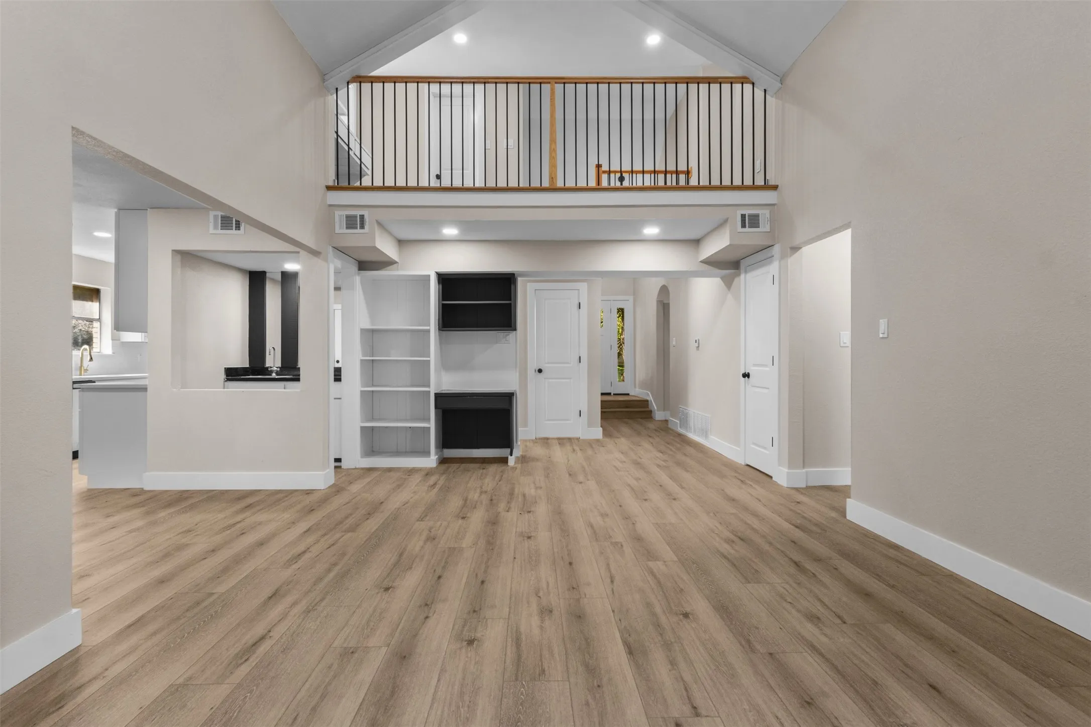 Spacious open-concept living area featuring vaulted ceilings and wood-finish flooring