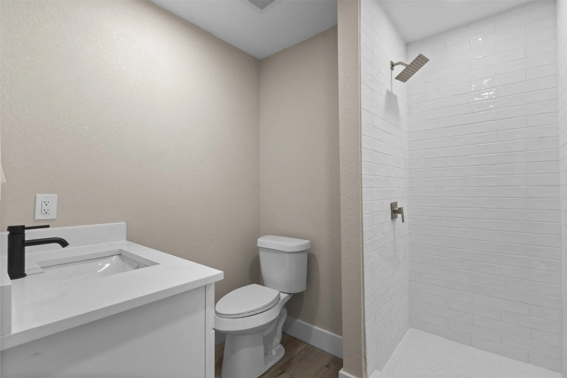 Bathroom featuring a walk-in shower with white horizontal tile, a rain shower head, and a built-in toilet