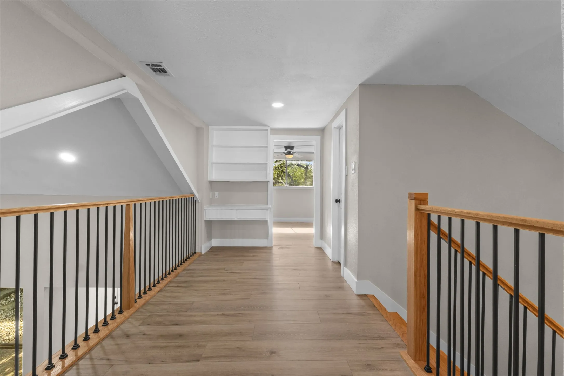 Upper-level hallway featuring wood-finish flooring, light-toned walls, and recessed lighting