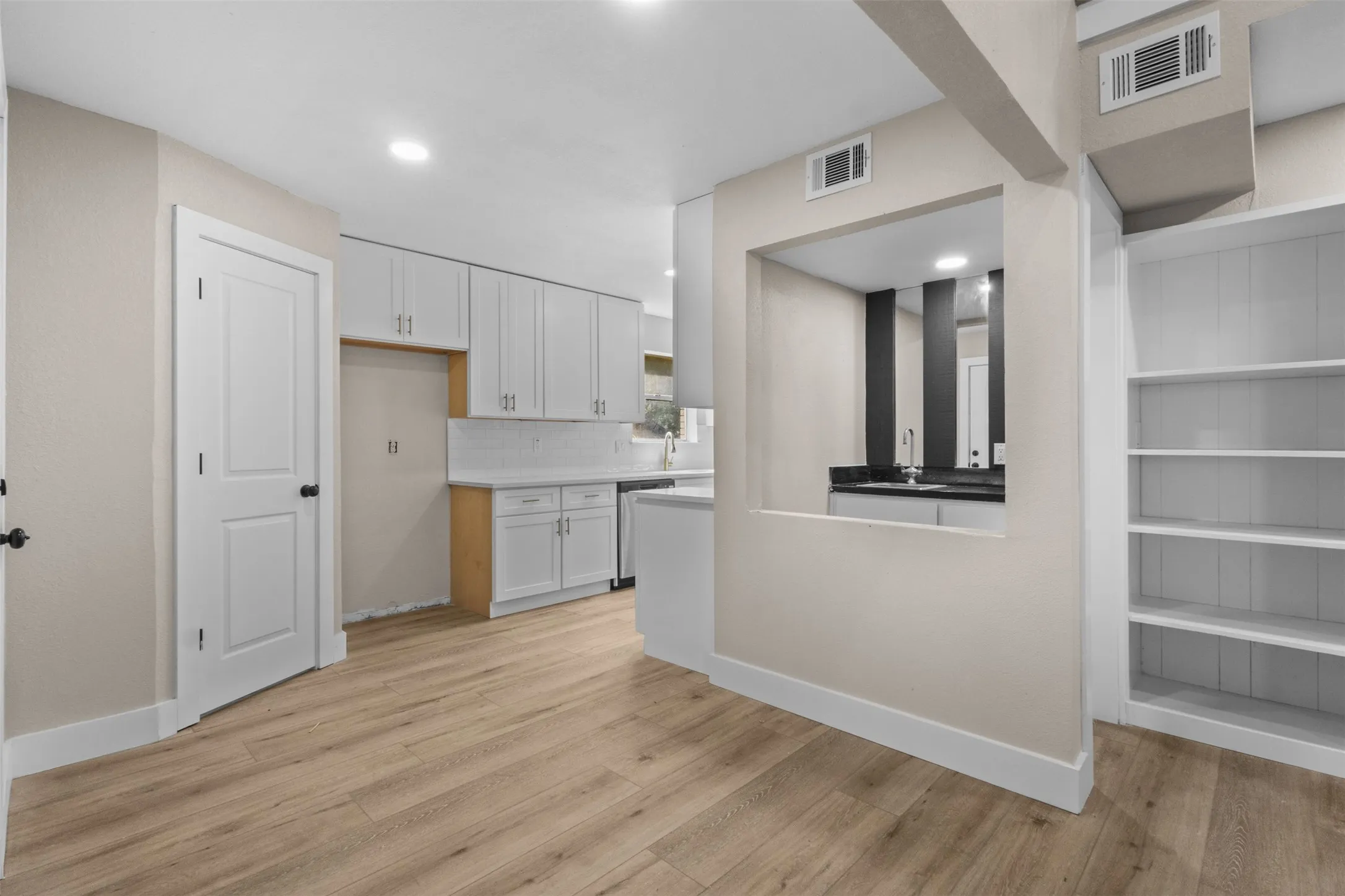 Open-concept living space featuring wood-finish flooring, recessed lighting, and a pass-through window to the kitchen