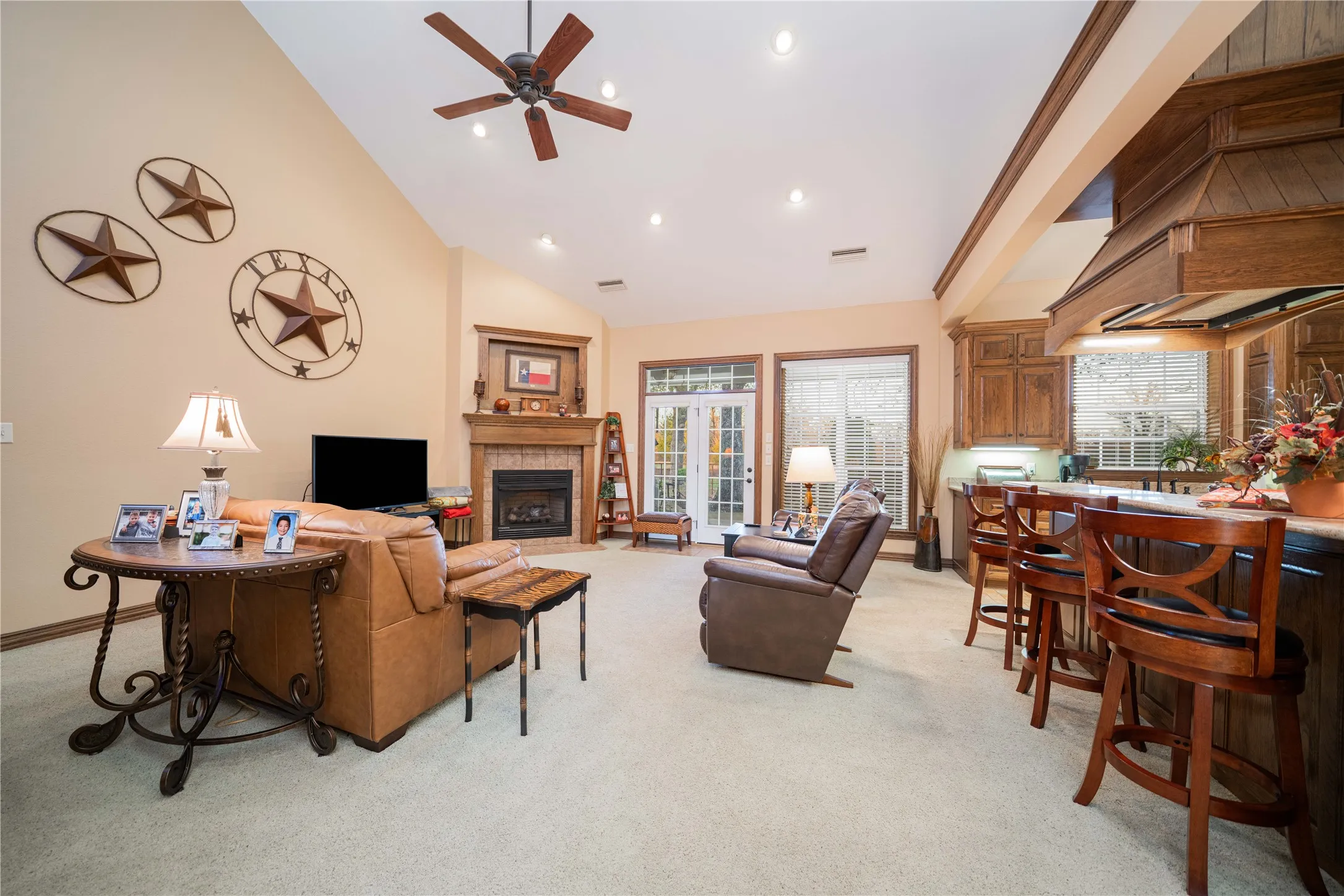 Open-concept living space featuring vaulted ceilings, a ceiling fan, recessed lighting, and a corner fireplace with a wooden mantel