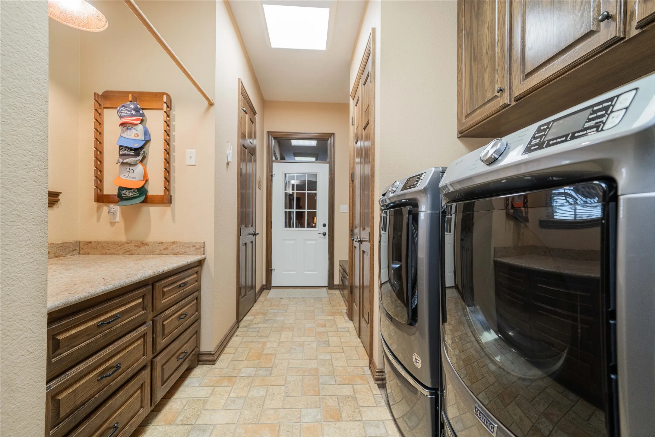Utility room featuring extensive built-in cabinetry, durable countertop space, overhead storage, and a skylight for natural illumination