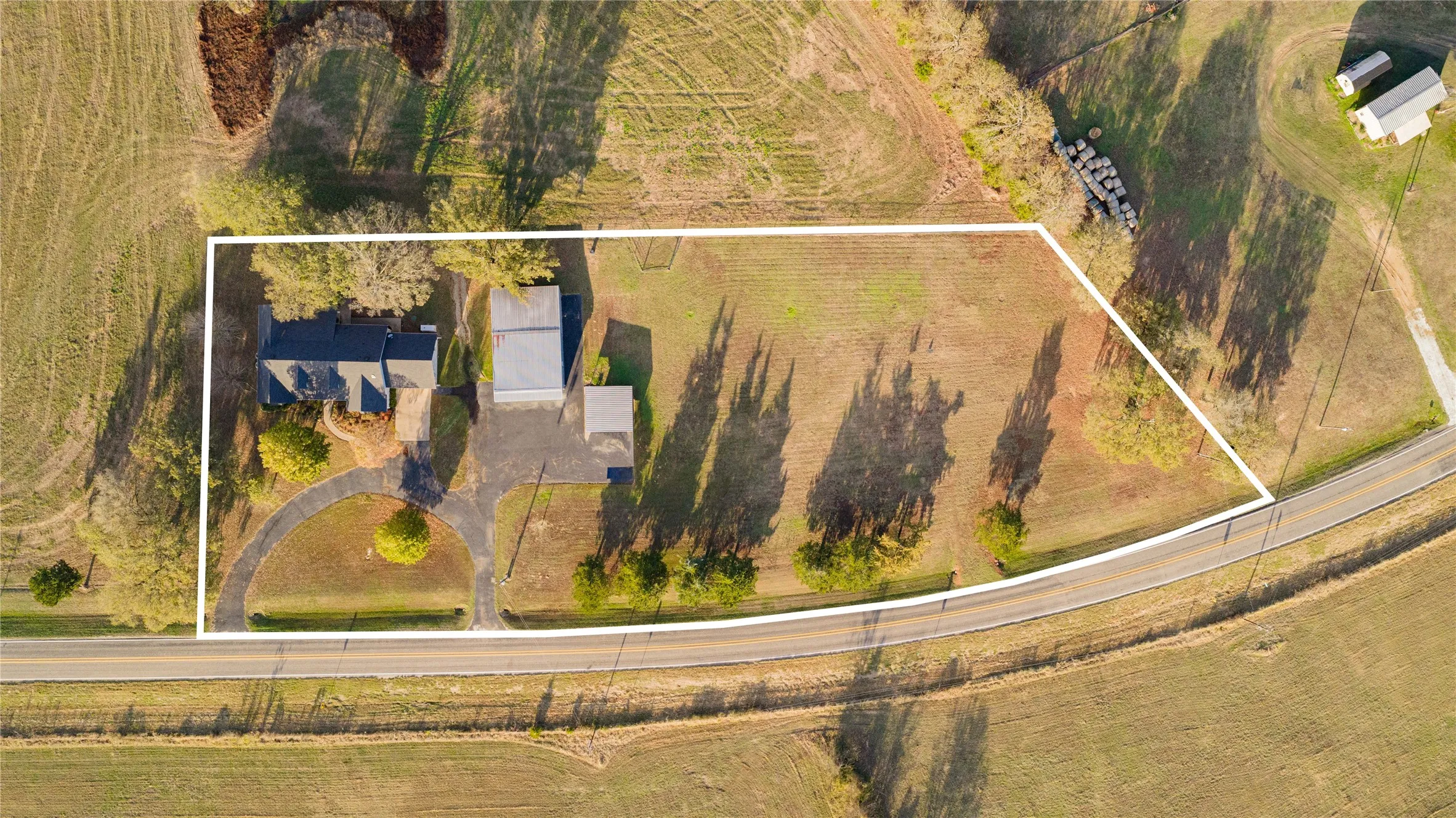Aerial overview of a single-family residence with an expansive surrounding property