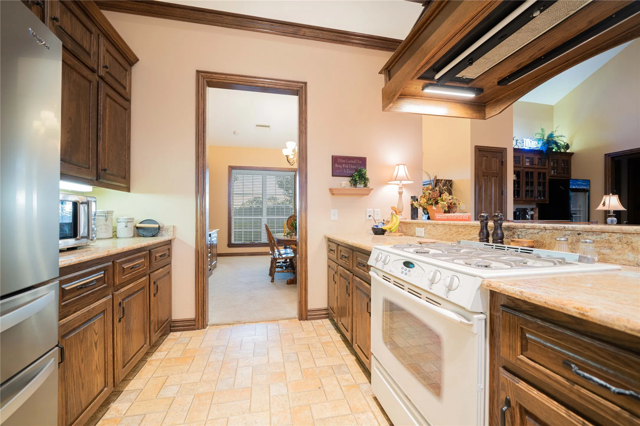 Kitchen featuring wood cabinetry, stone-finish countertops, and tile flooring arranged in a herringbone pattern