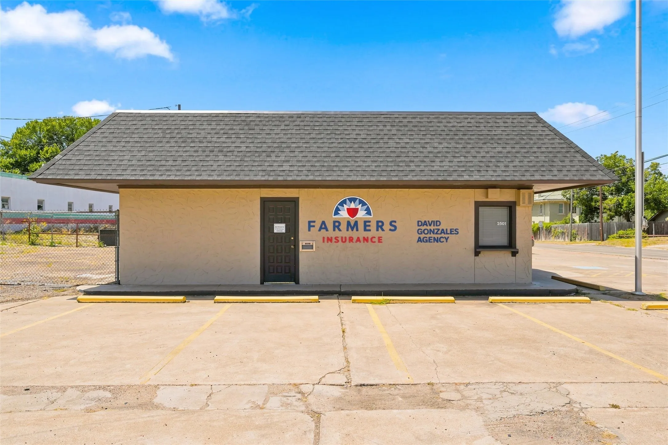 Commercial building featuring a gabled roof with asphalt shingles, a stucco exterior, and a solid entry door