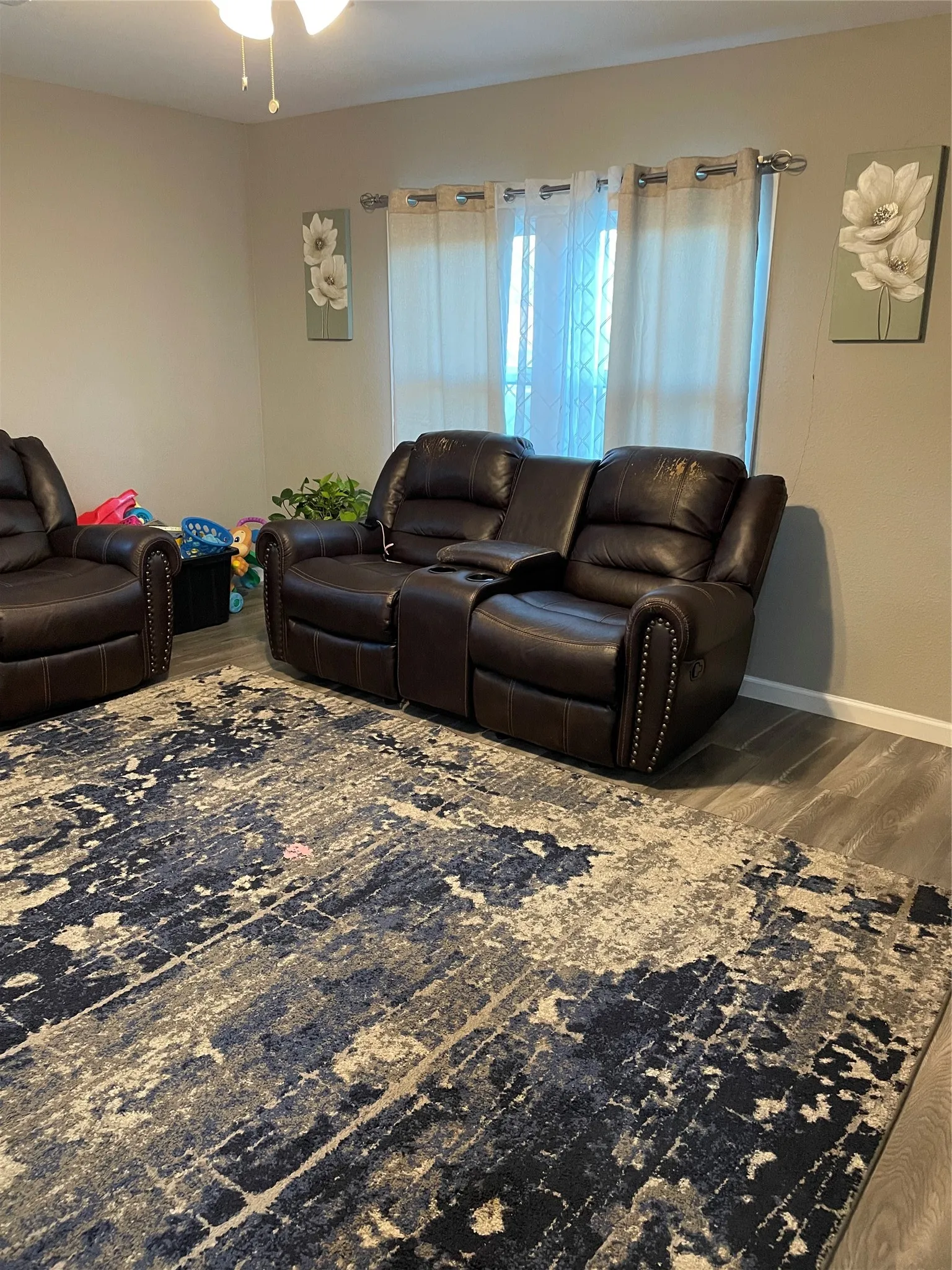 Living area featuring wood-finish flooring, neutral wall tones, and a ceiling fan with light fixture